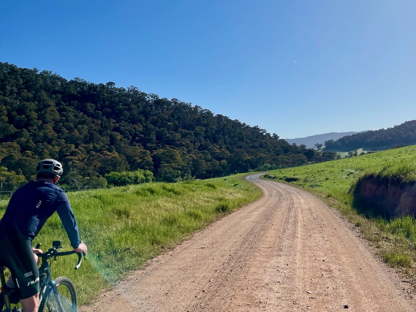 Cyclist riding on a gravel road through farmland 