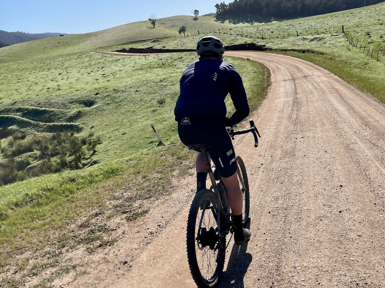 Cyclist riding through open farmland and rolling hills on a smooth gravel road