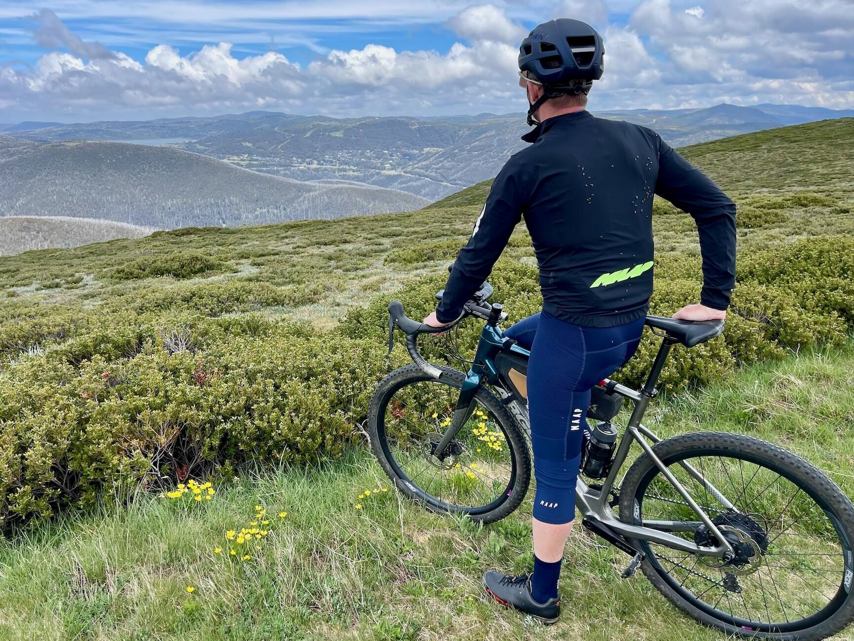 Cyclist stopped on top of a ridge to see the surrounding mountains and Falls Creek Resort