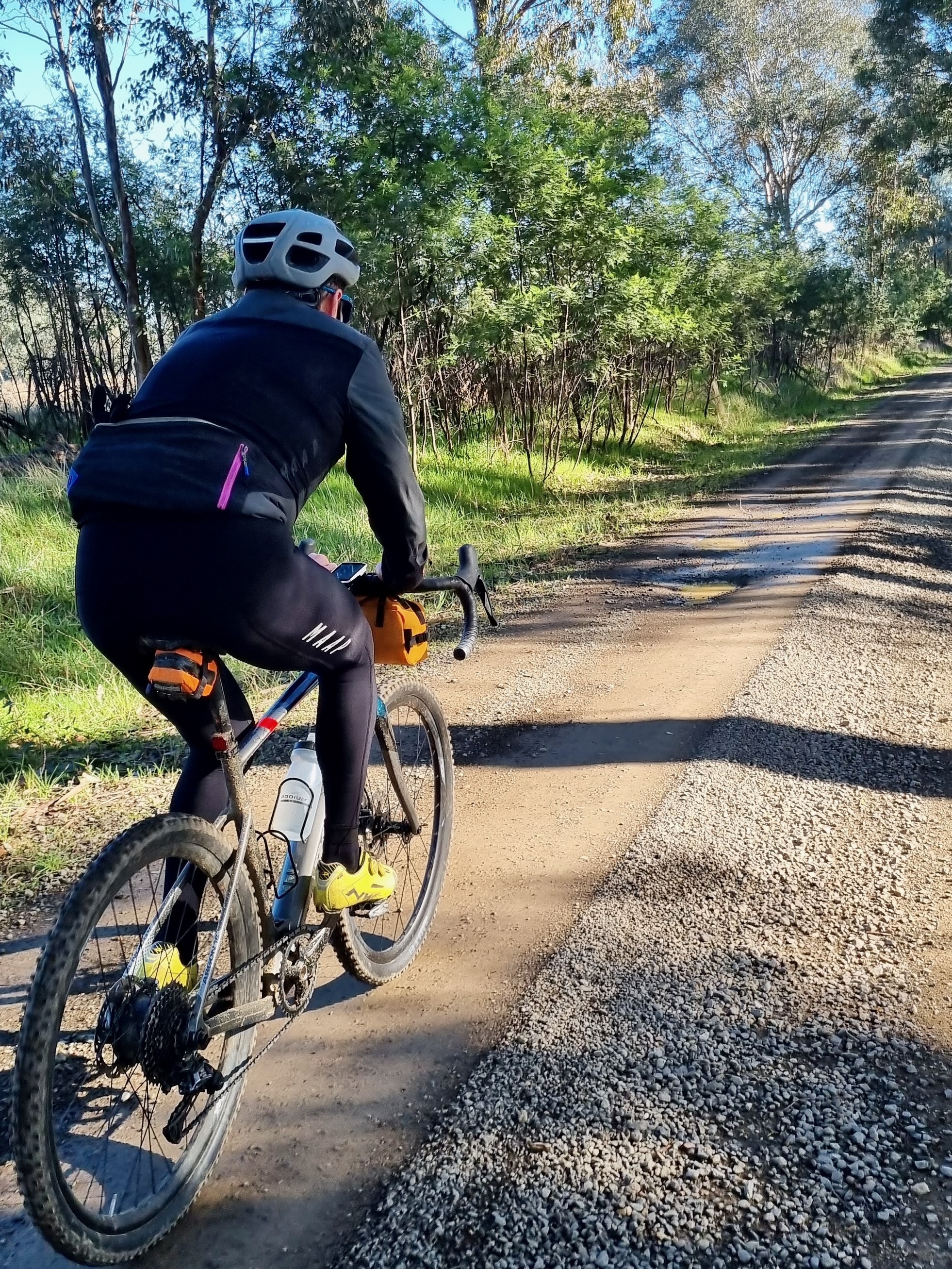 A cyclist riding through native bushland on a smooth gravel road