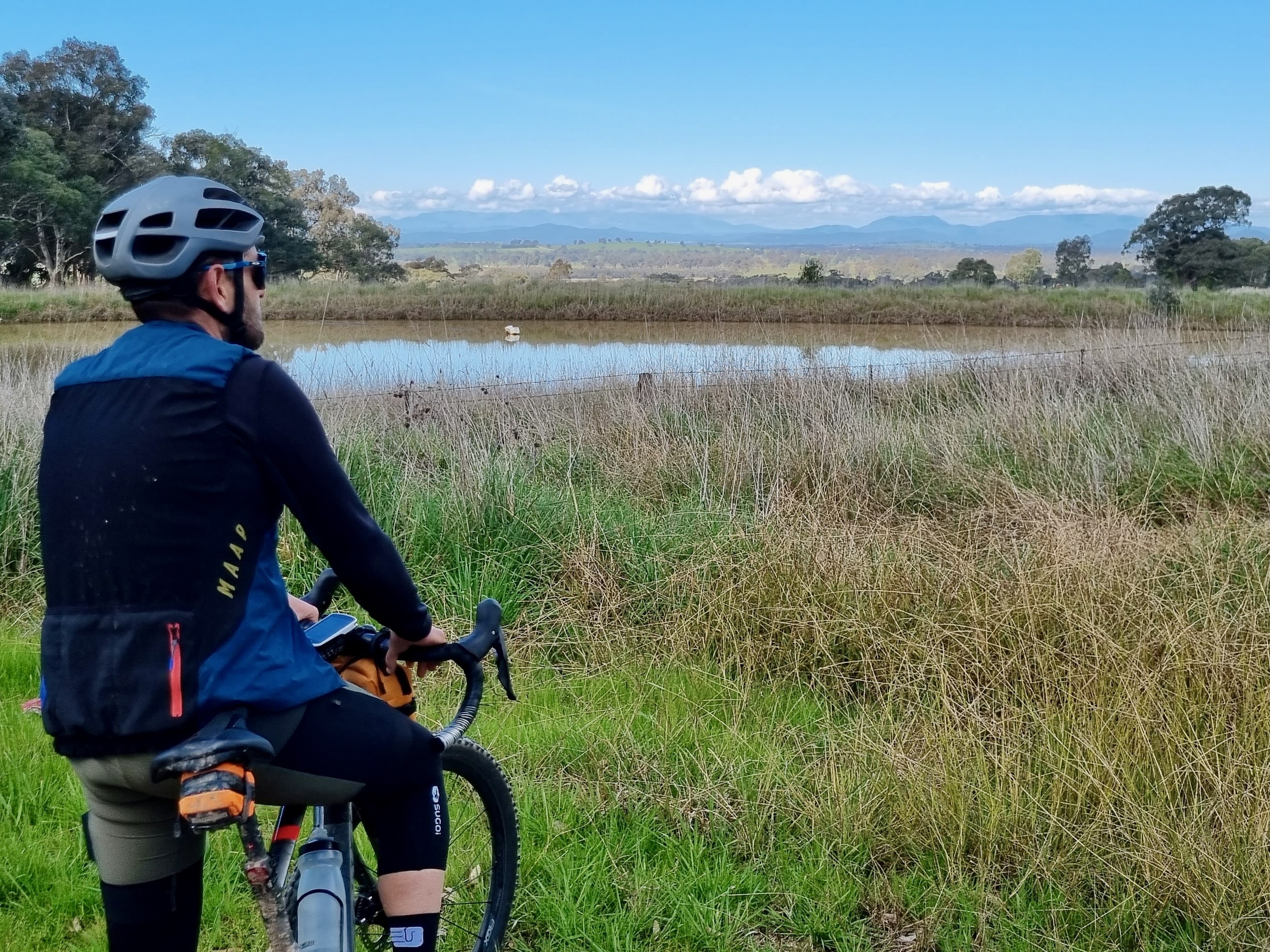Cyclist stopped in front of dam looking at mountain range in the distance