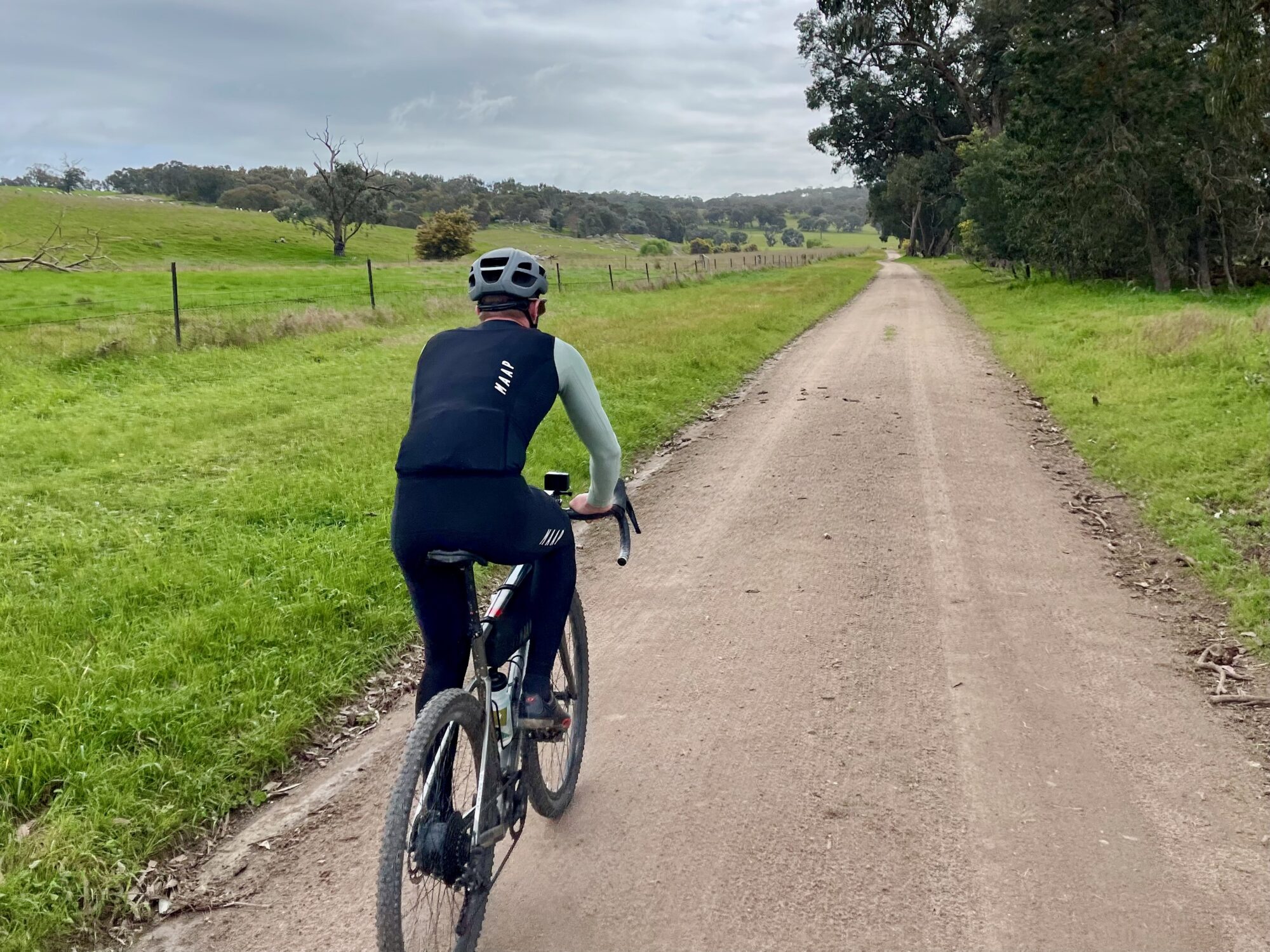 cyclist riding on smooth gravel road through open farmland