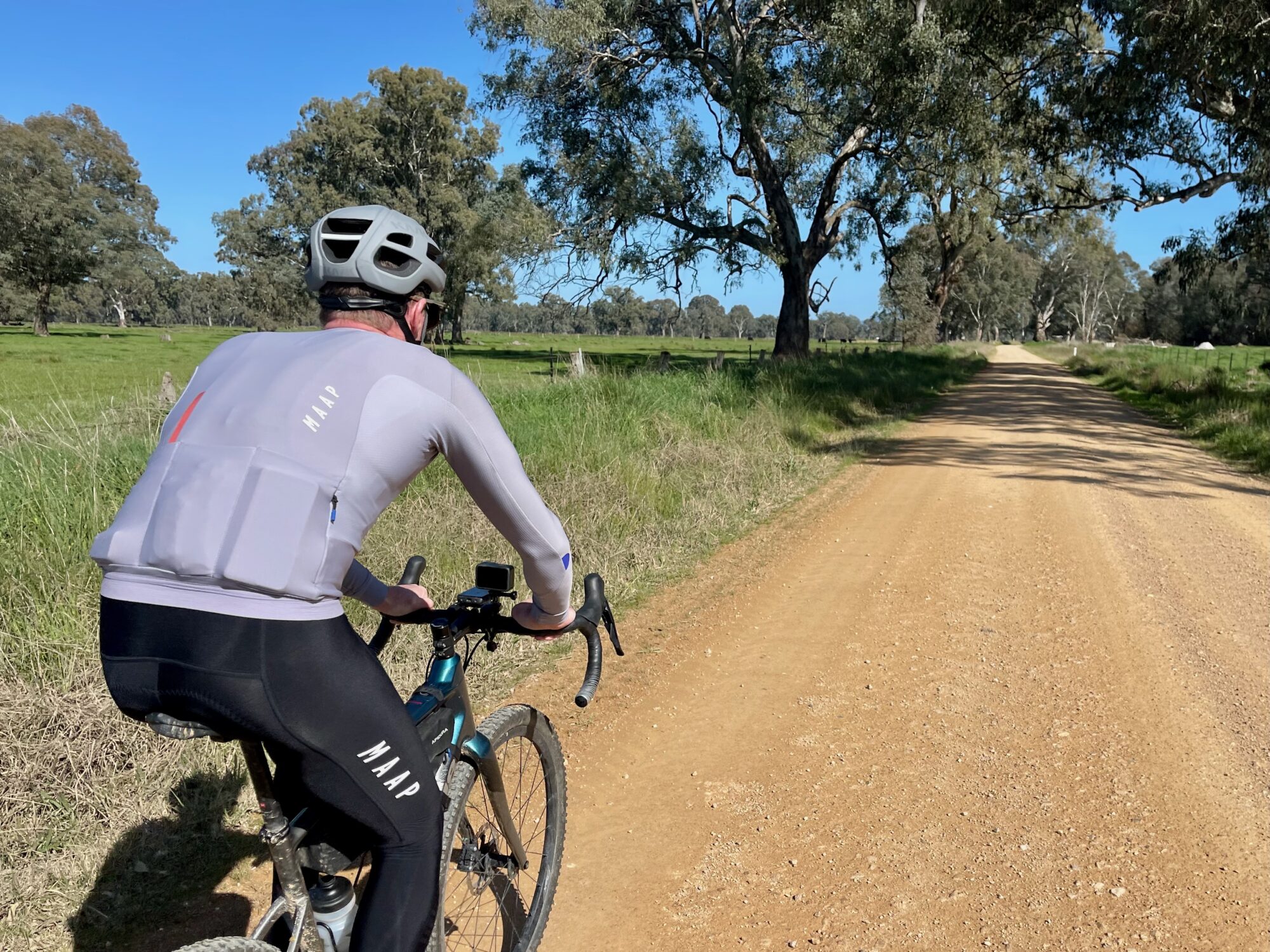 Cyclist riding on smooth gravel road with native trees in the distance