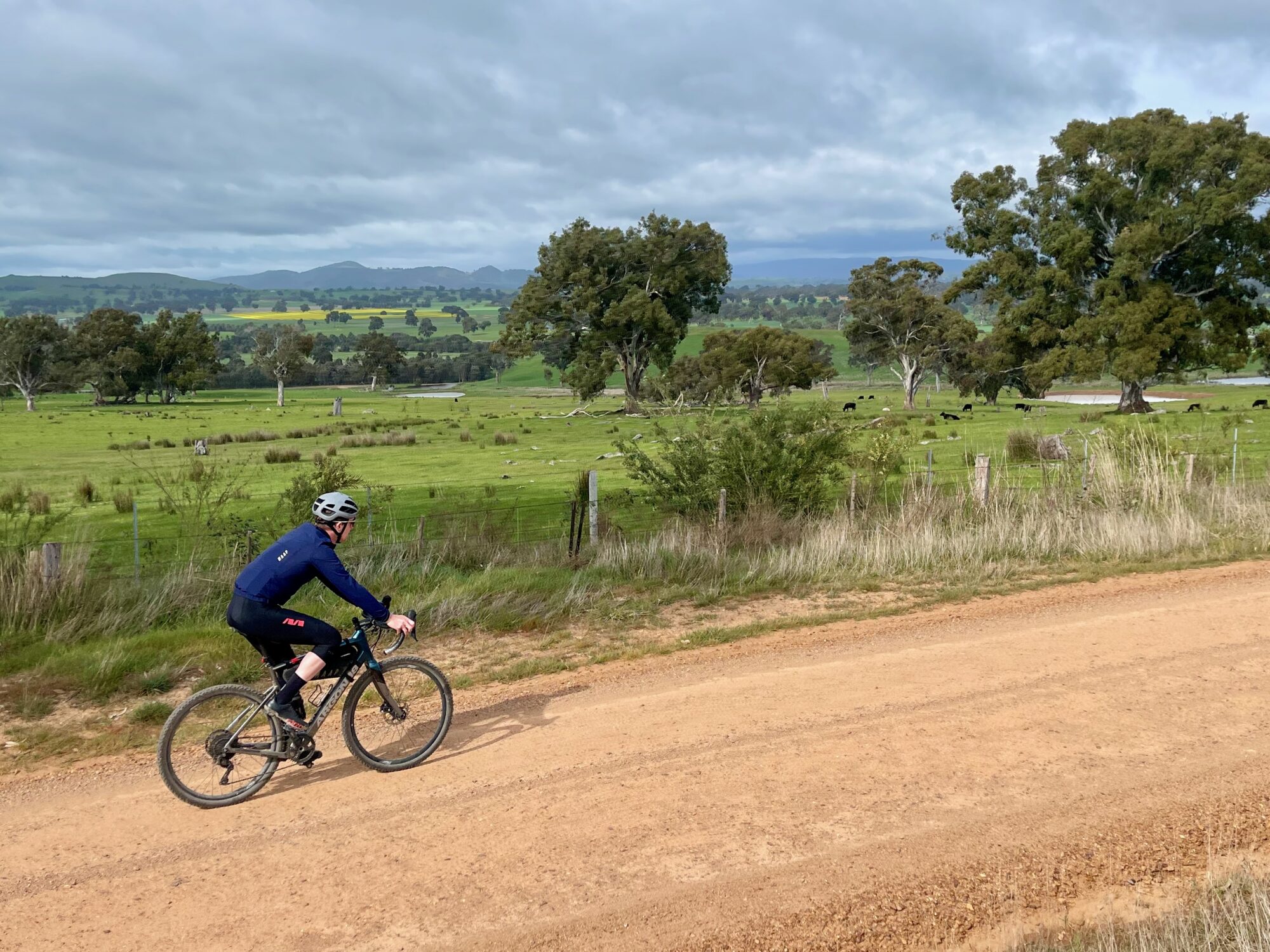 cyclist riding on gravel road beside farmland