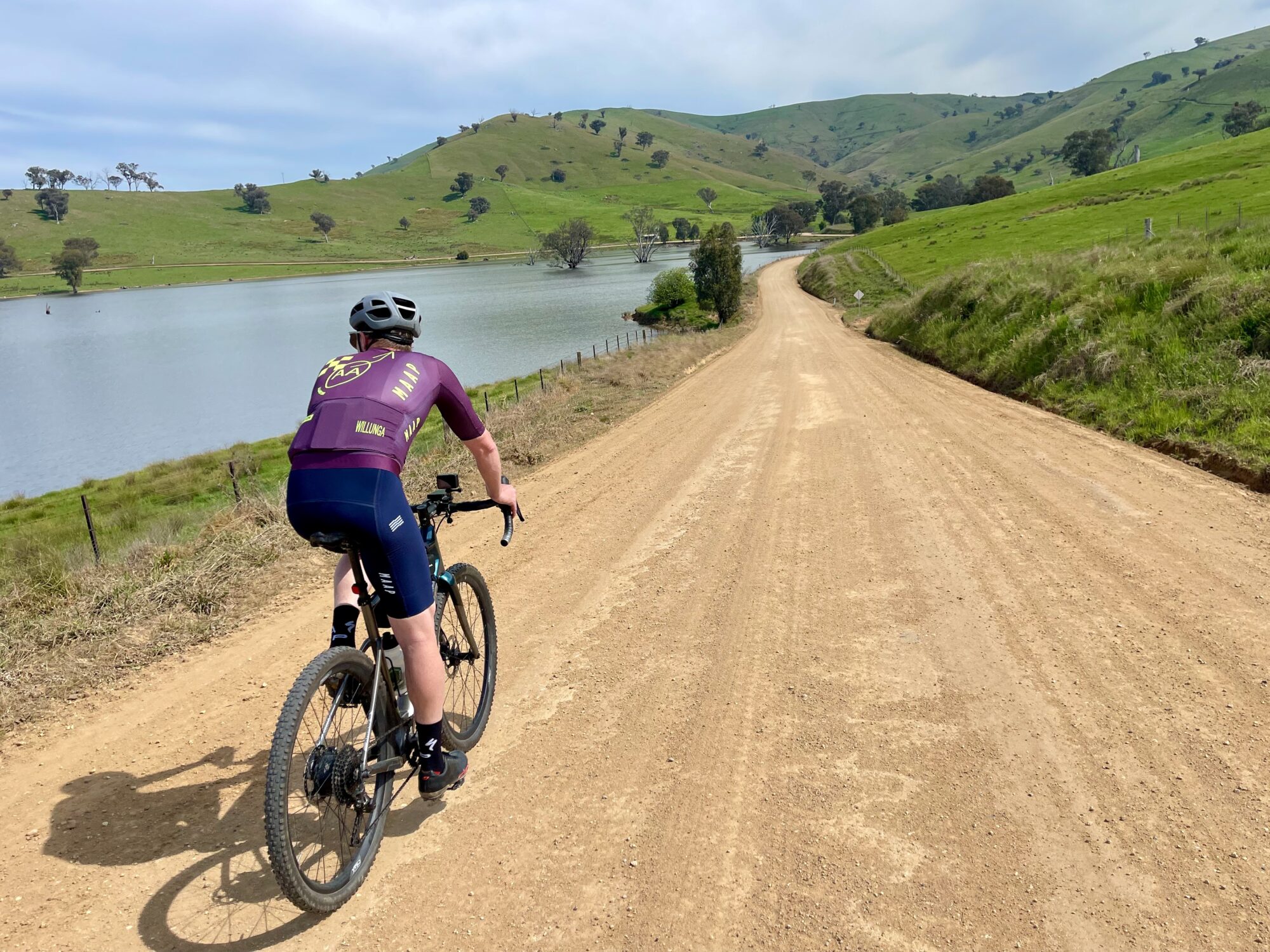 Cyclist riding on gravel road on the edge of lake 