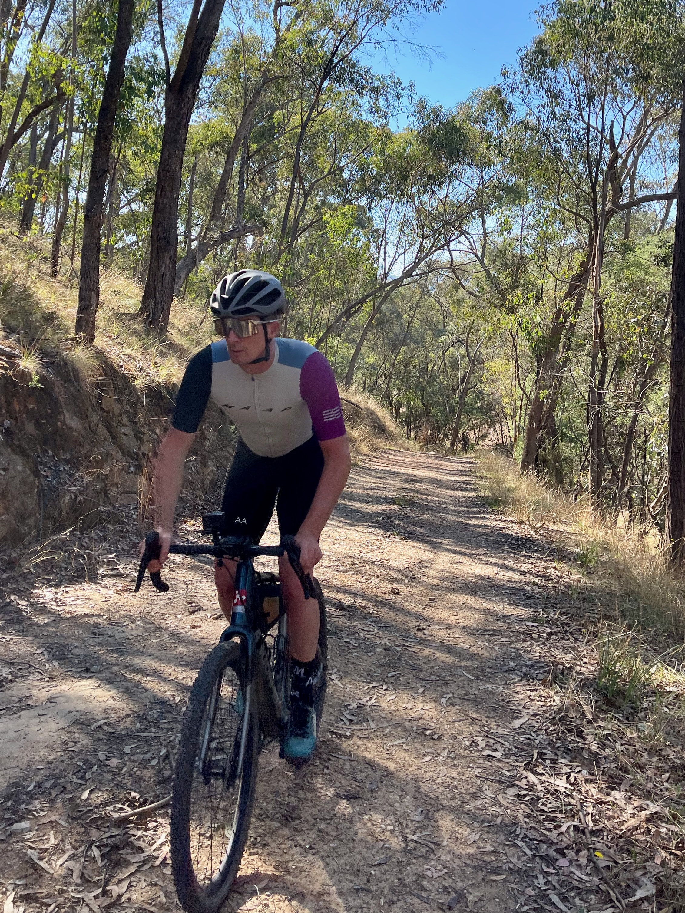 Cyclist standing up to climb a gravel roads in native bushland