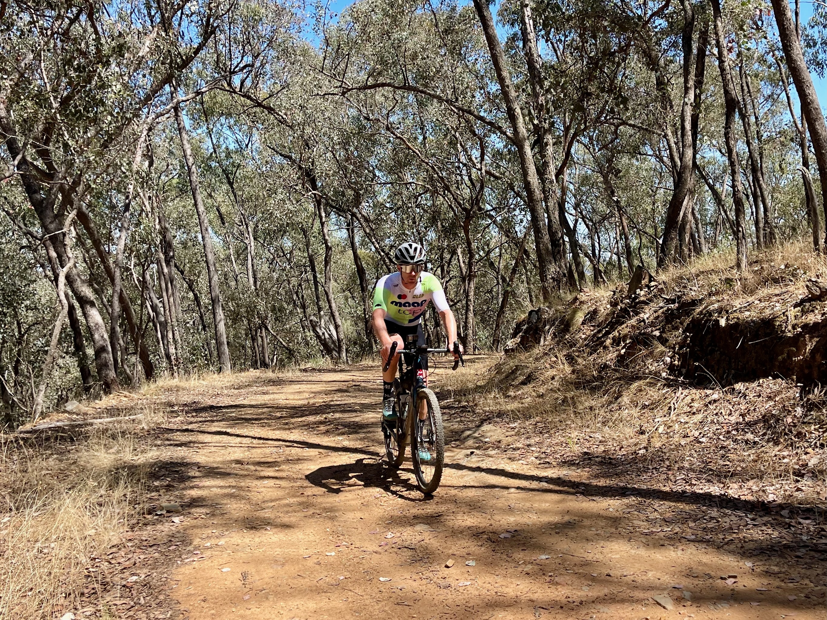Cyclist descending on a dirt rod with native bushland in the background