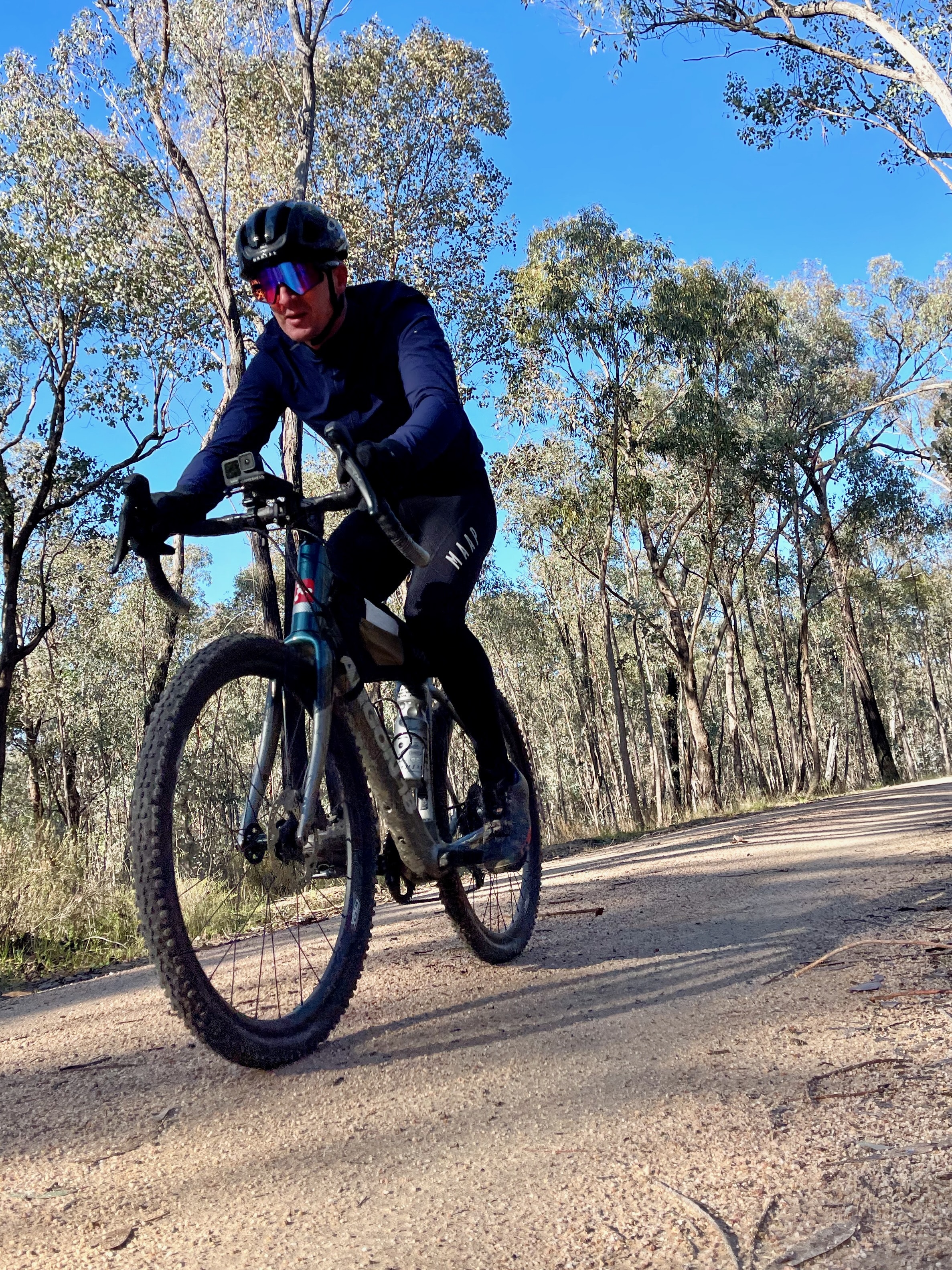 A cyclist riding on crushed granite road through native bush on a sunny day