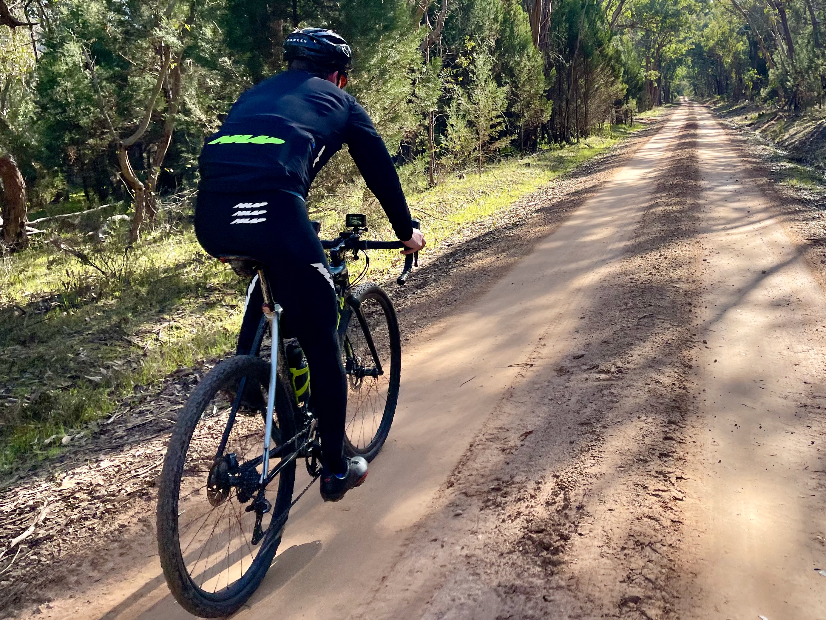 Cyclist riding on hard pack gravel road through native bushland