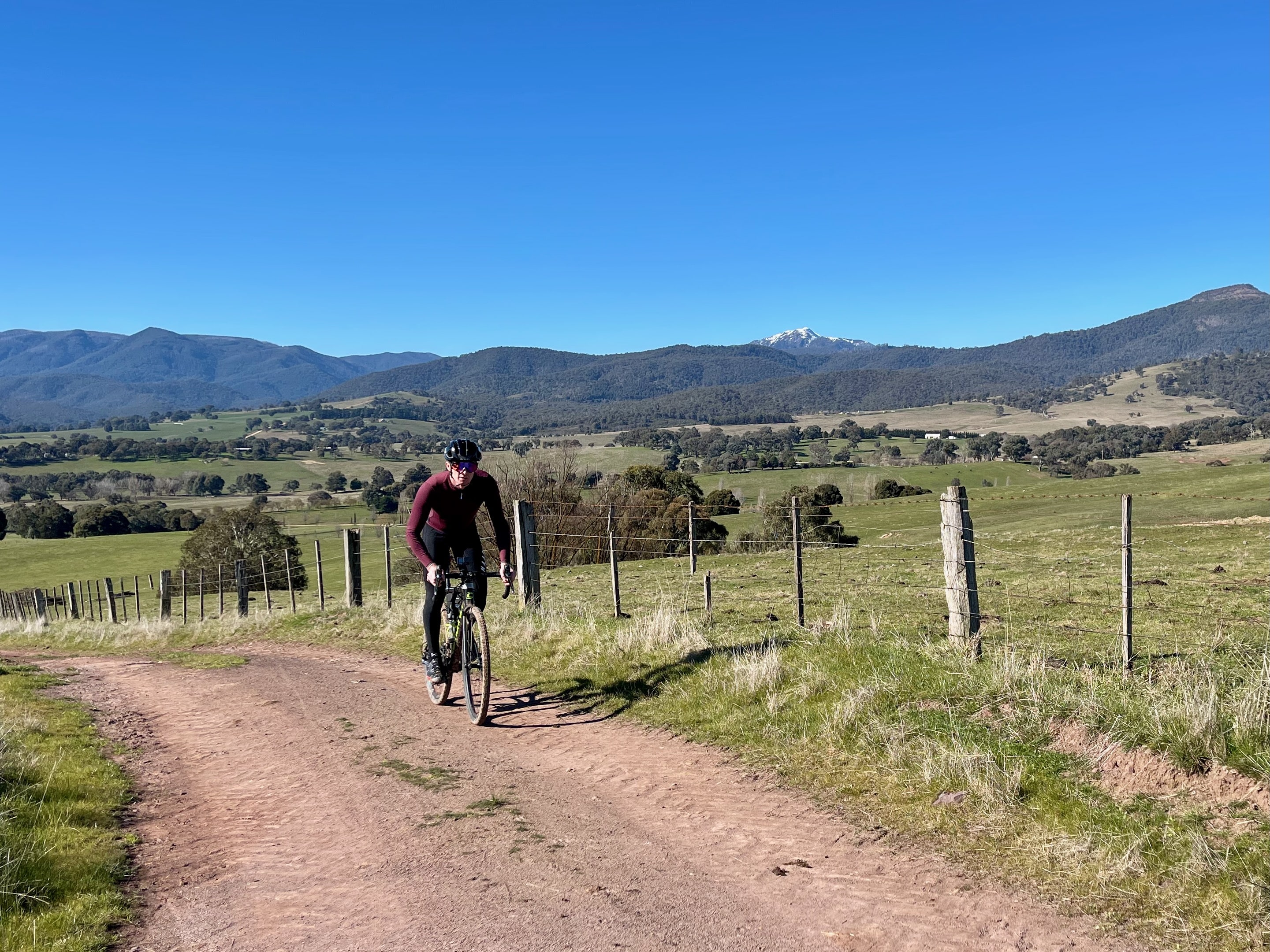 Cyclist climbing up a smooth gravel road with mountains in the background