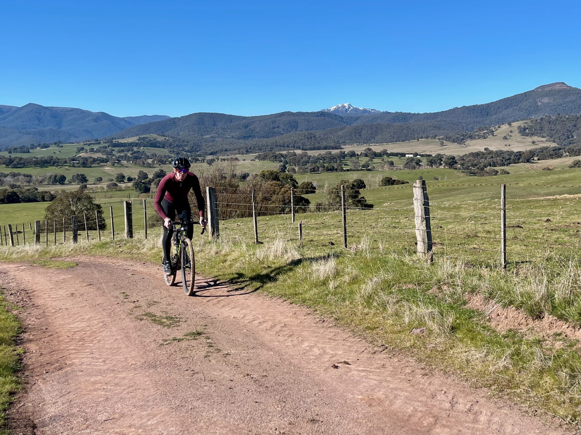 Cyclist riding on gravel road with Mt Buller in the background