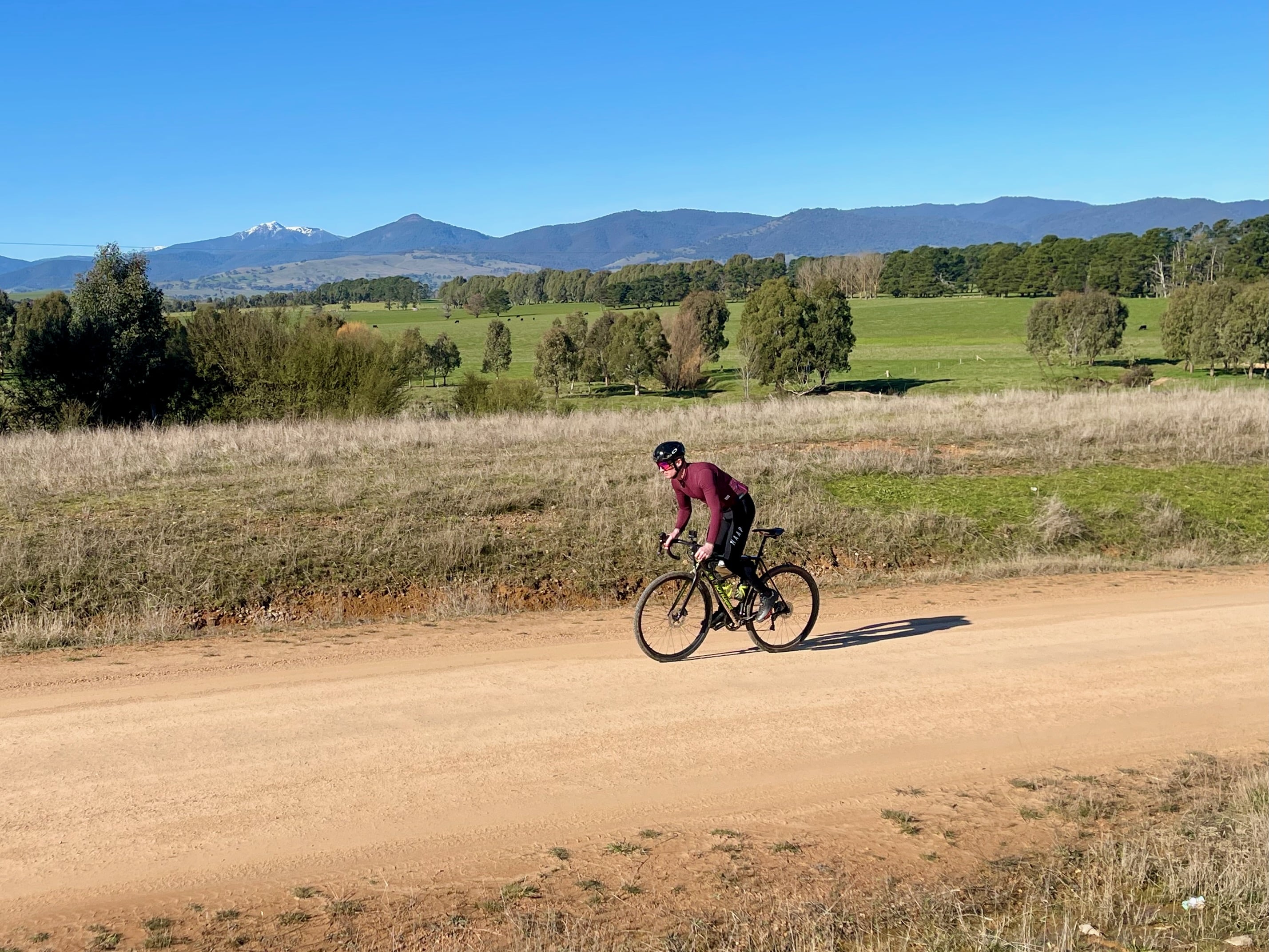 Cyclist riding smooth gravel road with Mt Buller in the background