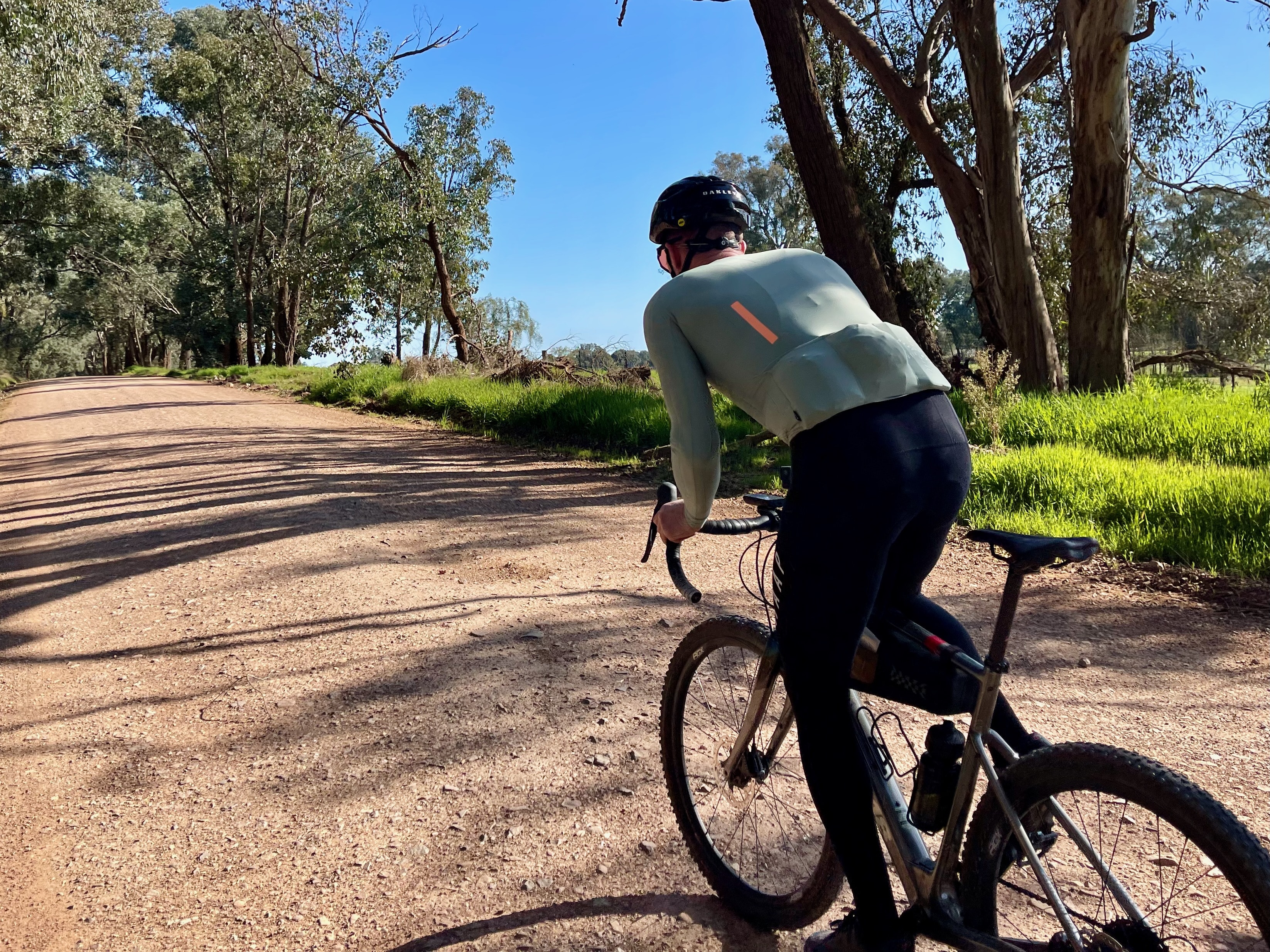 Cyclist climbing up a smooth gravel road surrounded by native bushland