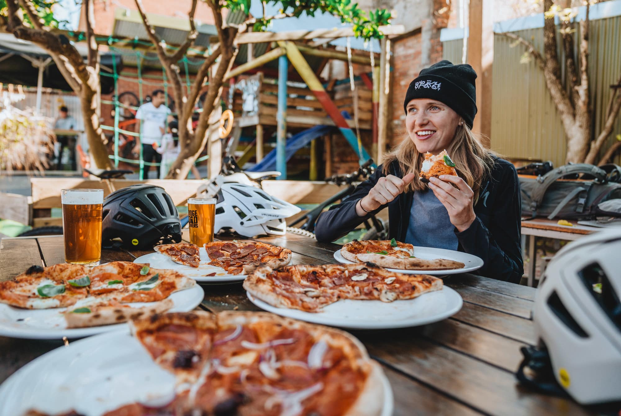 Cyclist celebrating after a ride at Beechworth Mountain Bike Park with Bridge Road Brewers beers and pizza