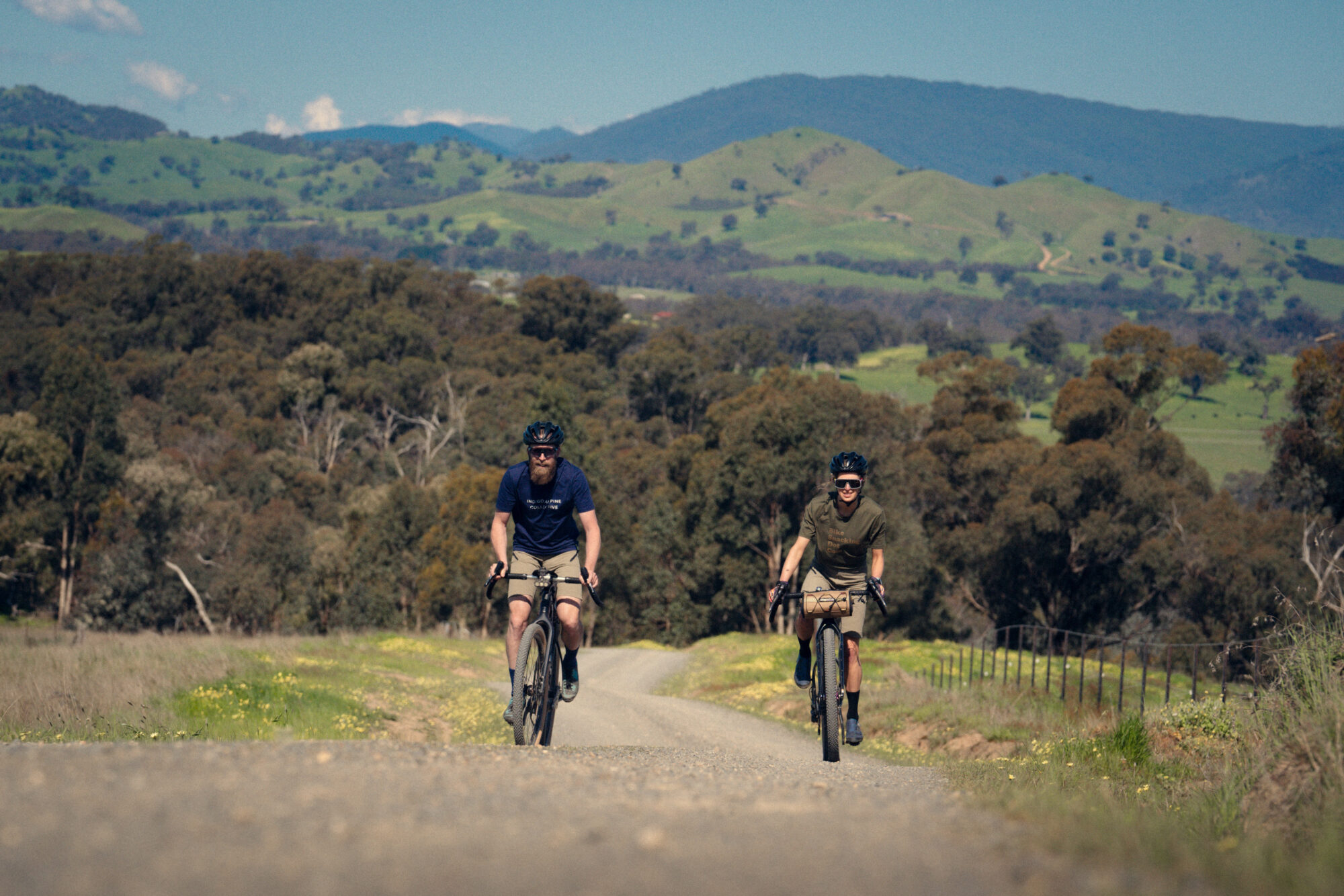 Two cyclists riding the gravel route of Goin to Bonnie Doon past hills and farmland