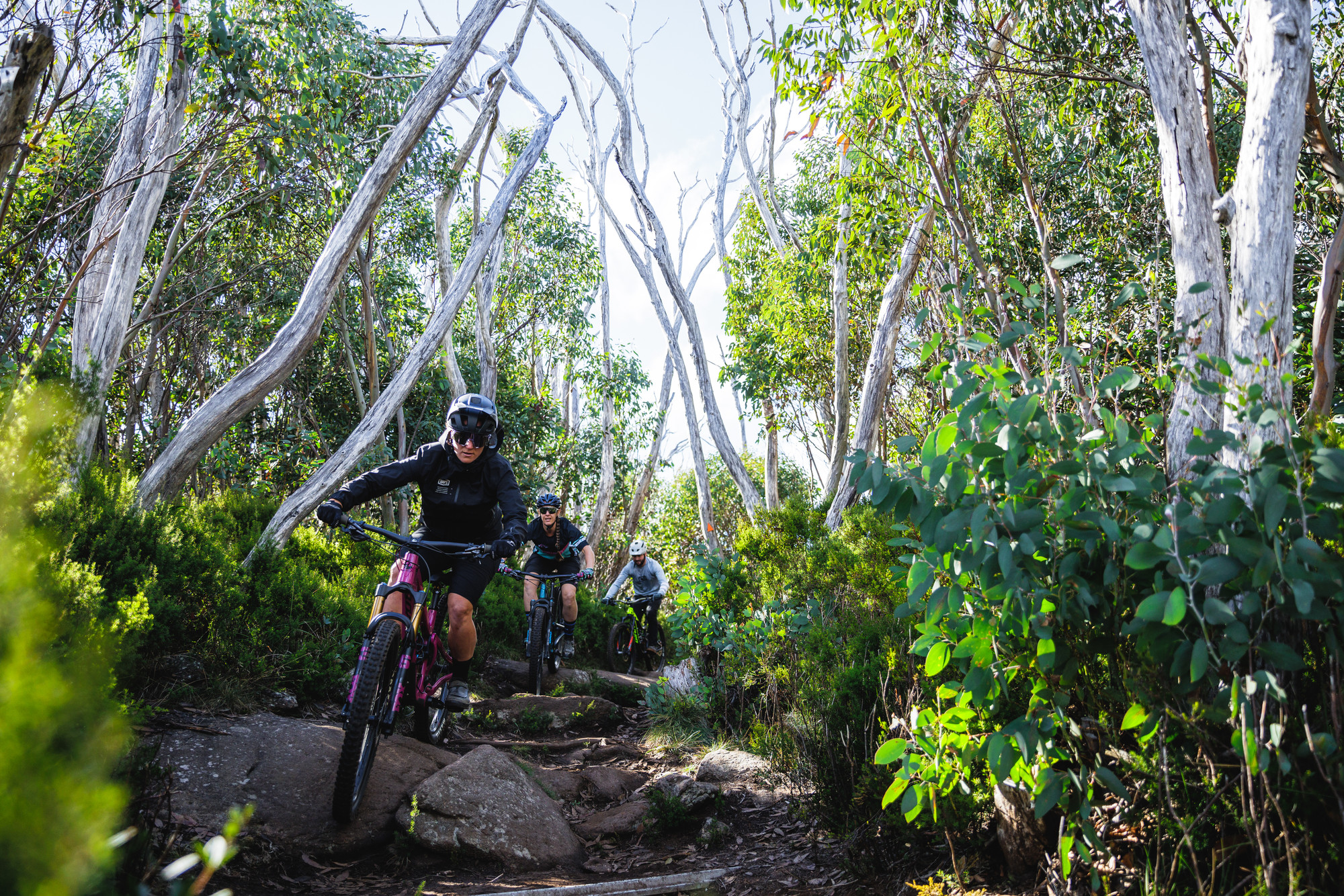 Cyclists riding over technical rock features on Cascades Trail