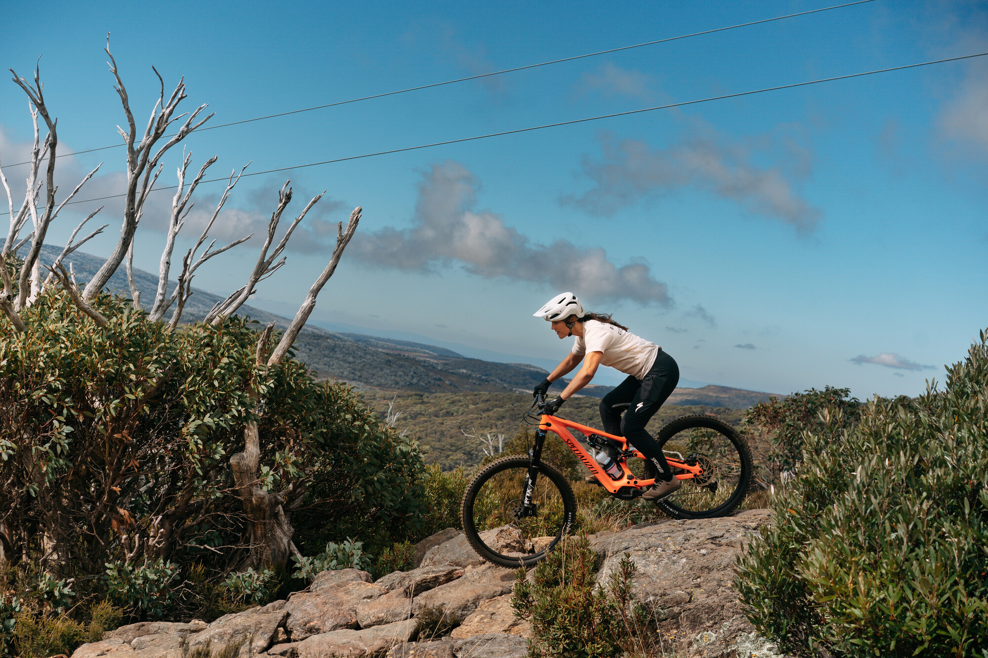 Cyclist riding over rock technical features at Falls Creek Mountain Bike Park