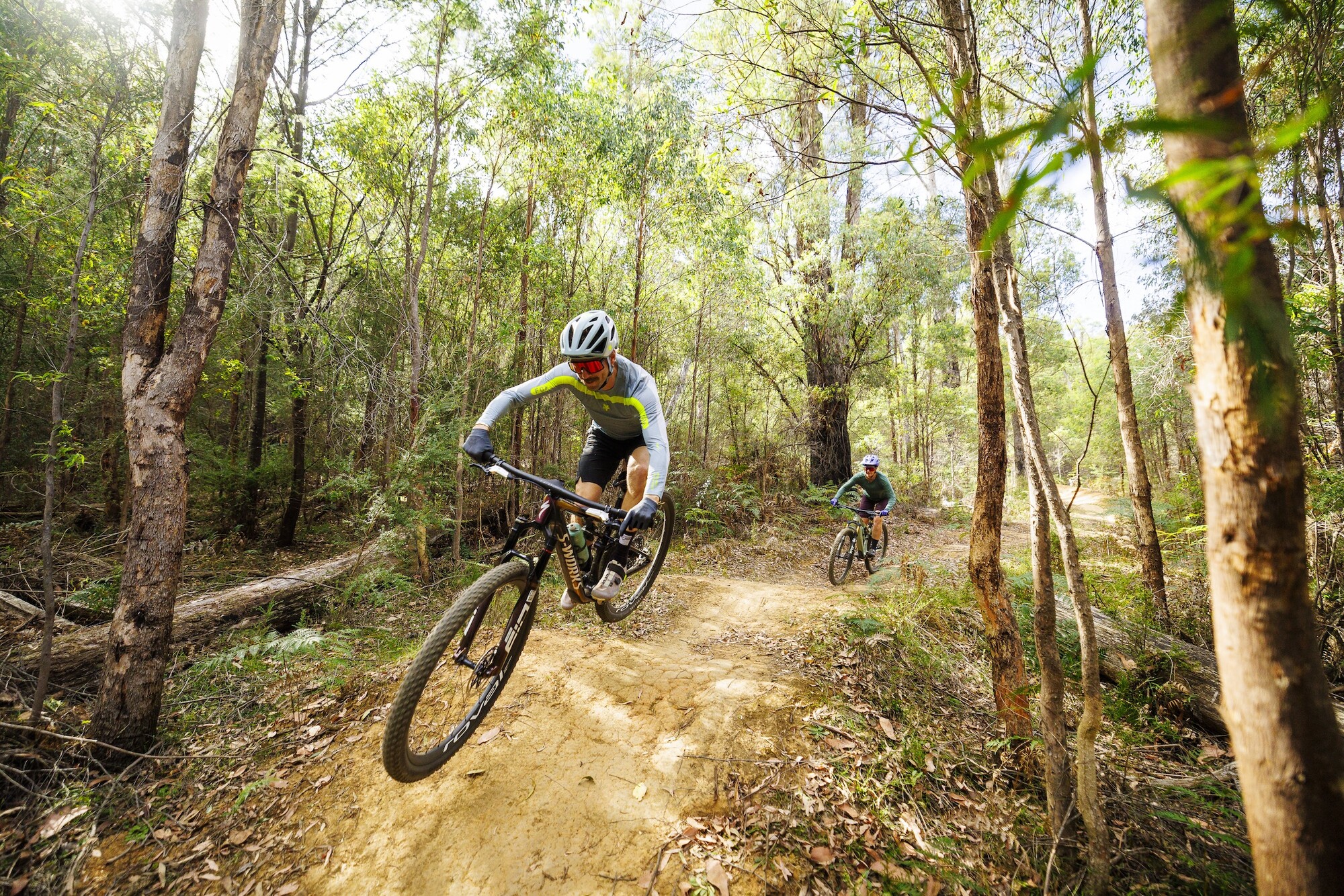 Two cyclists jumping over rollars and gaps at Buxton Mountain Bike Park