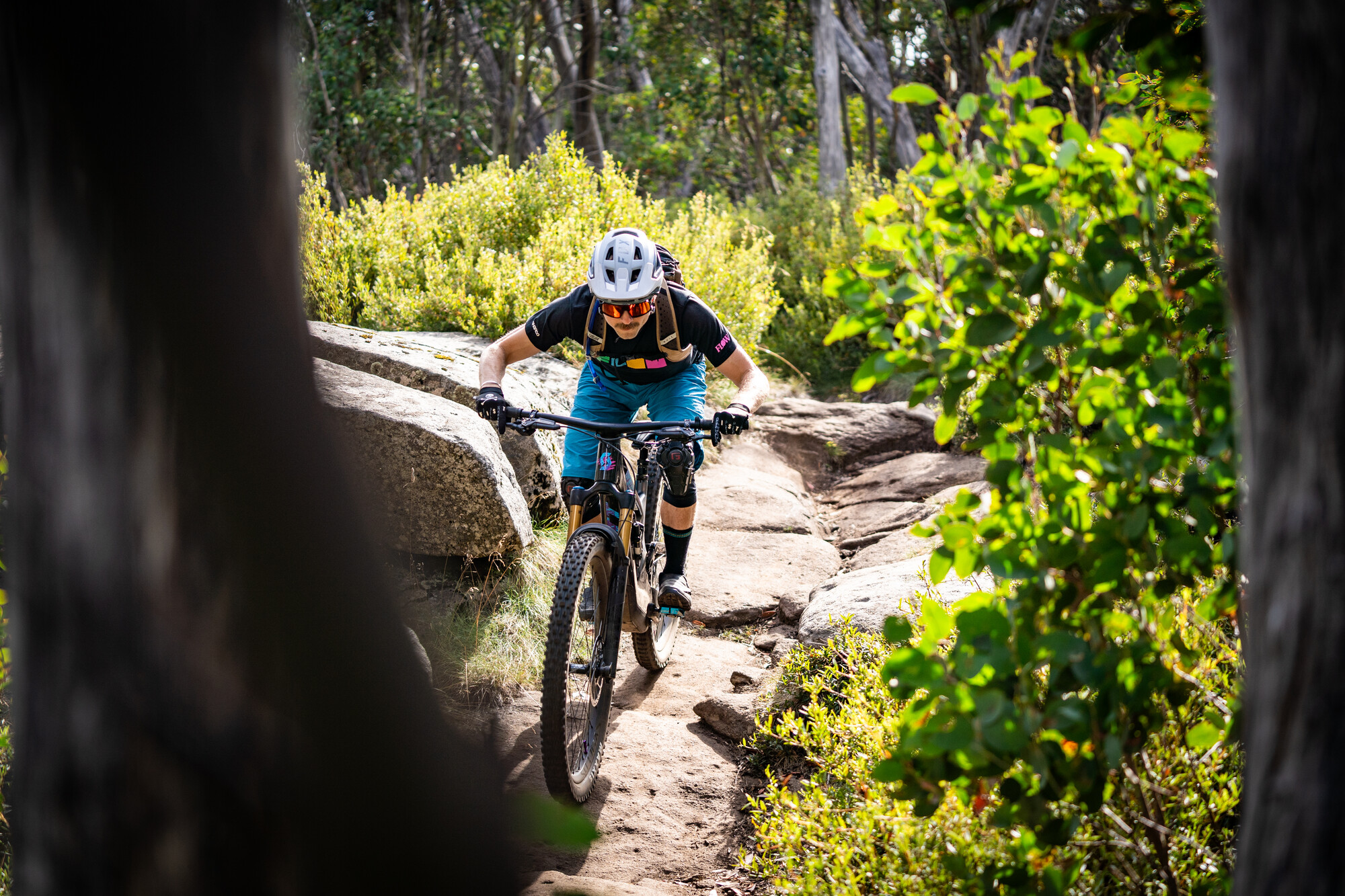 Cyclist riding over granite rock features at Lake Mountain Bike Park