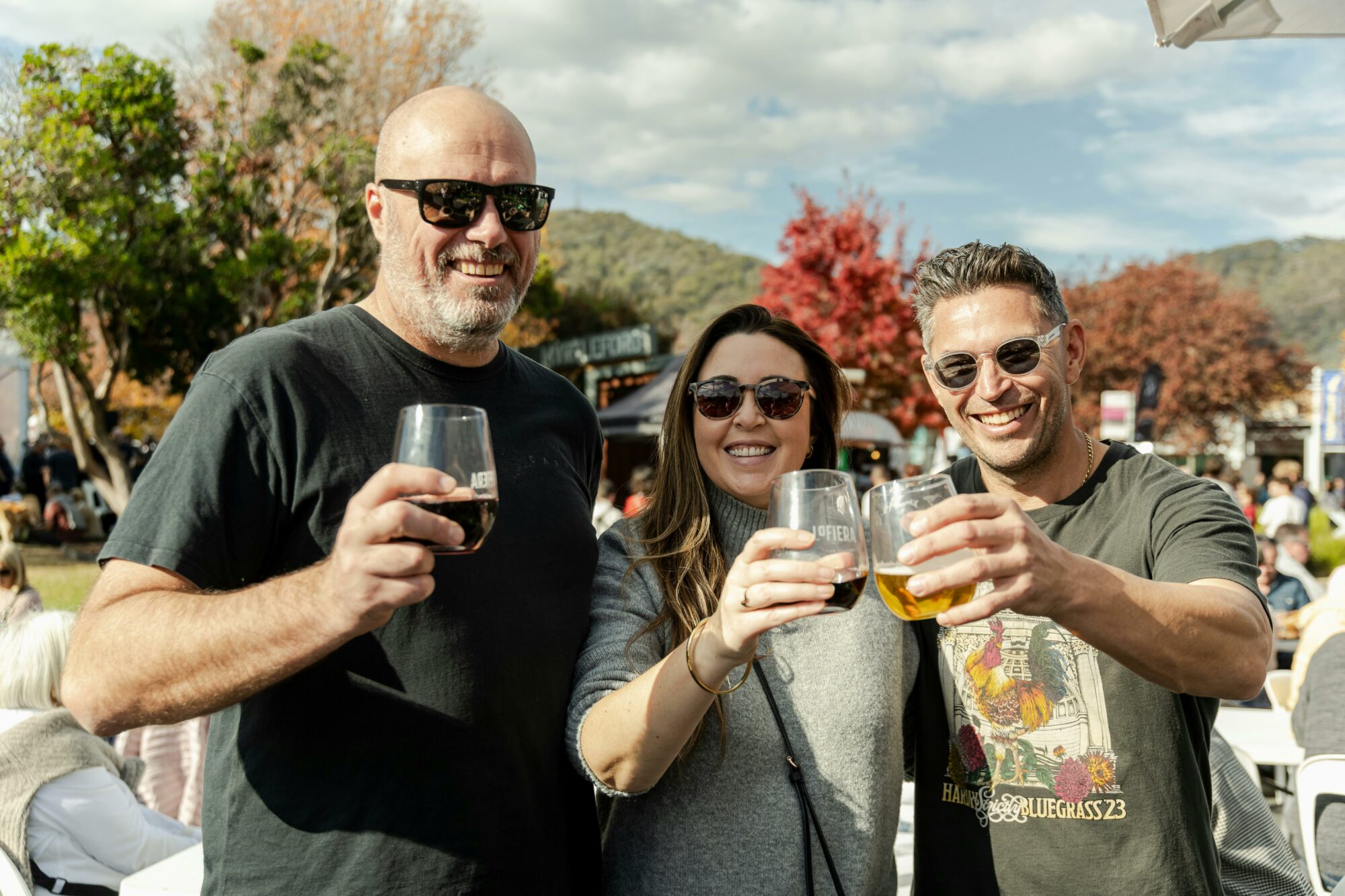 two men and a woman posing with some drinks in hand