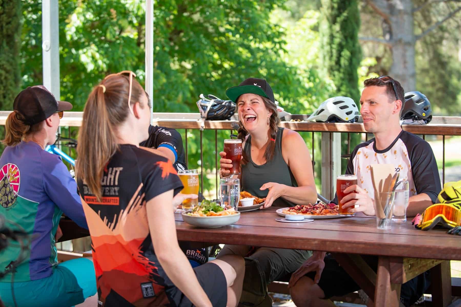 Four people sit around a table outside, eating food and drinking beer.