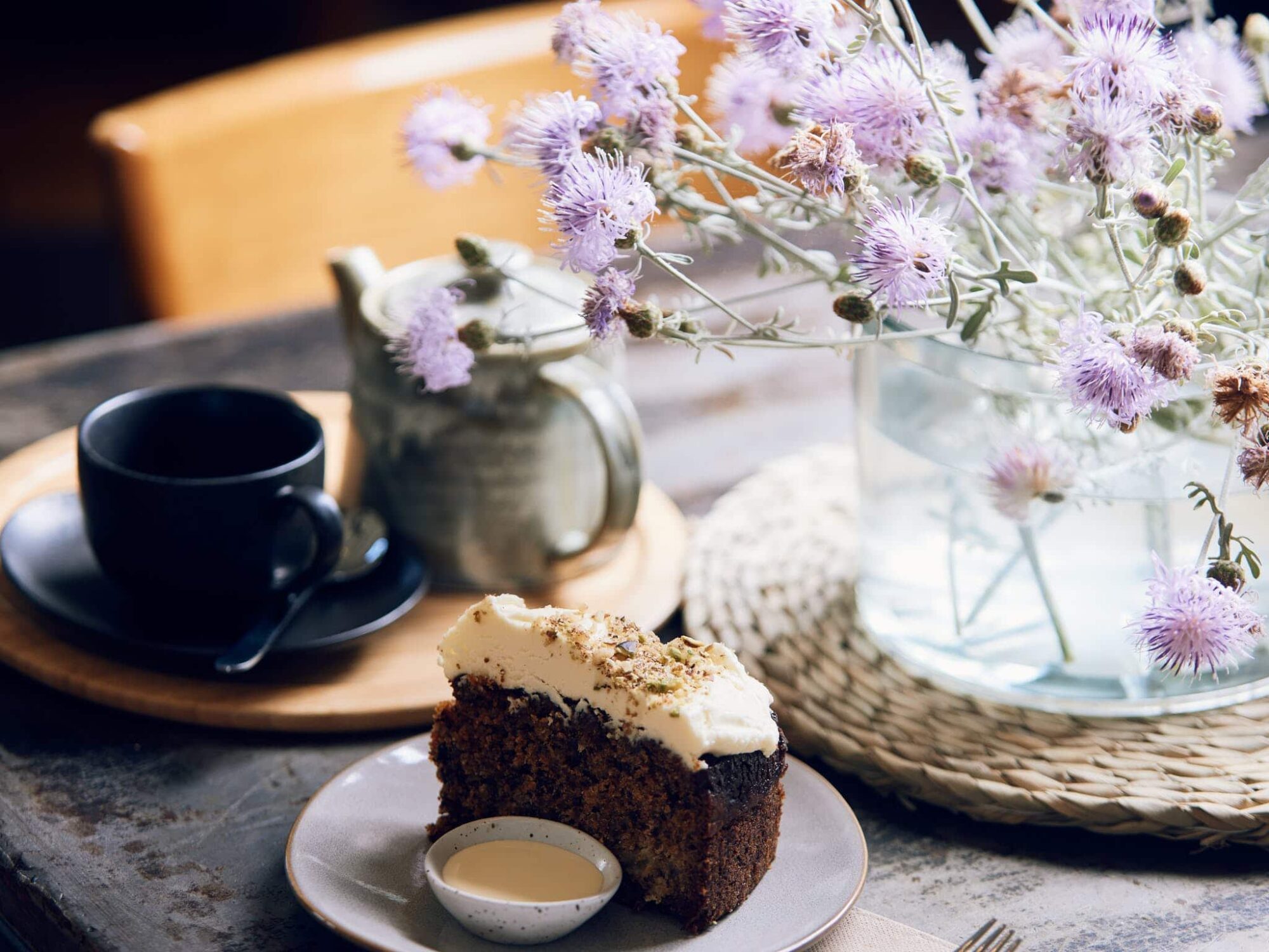 Tea, cake, flowers plated up on a table at Dindi Cafe