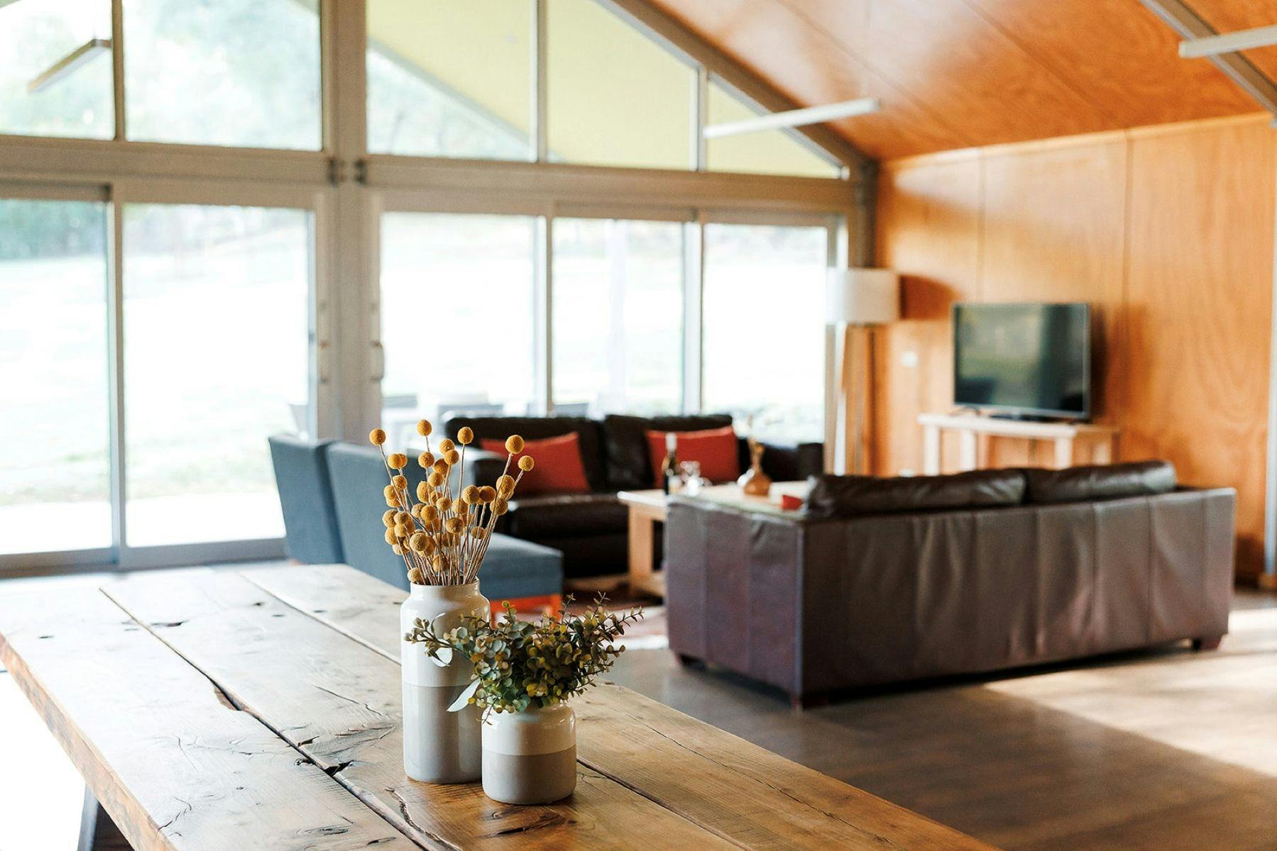 Warm toned loungeroom with brown leather couch, timber dining table and blue occasional chairs