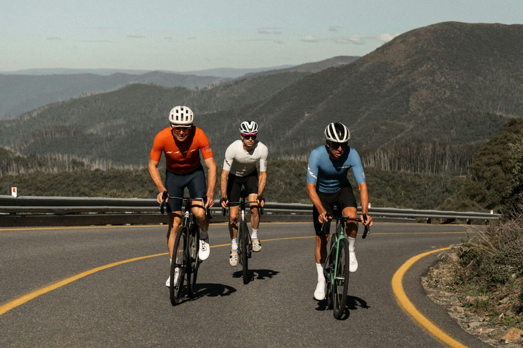 Three cyclists riding past mountain views on the Mt Hotham 7 Peaks Challenge route.