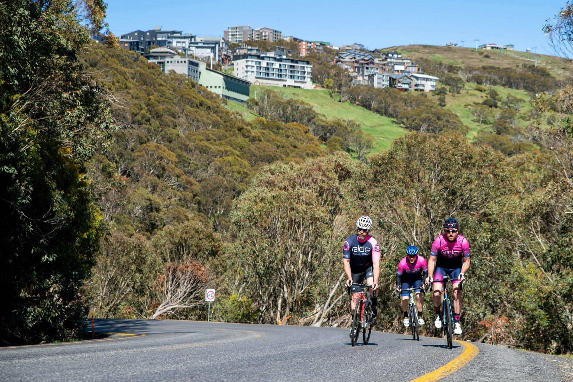 Group of cyclists riding the Mt Buller road with the Mt Buller village in the background