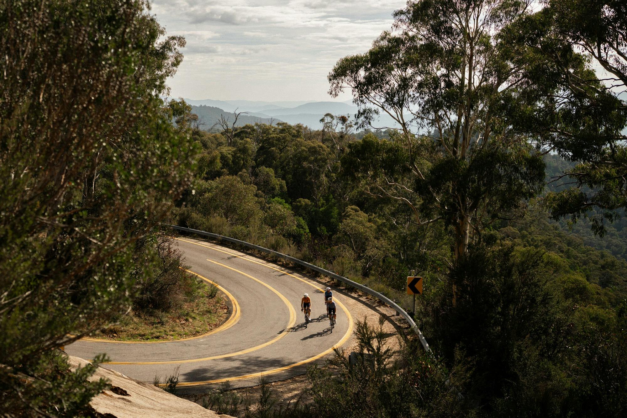 Three cyclists riding around a hairpin turn on the Mt Buffalo 7 Peaks Challenge route