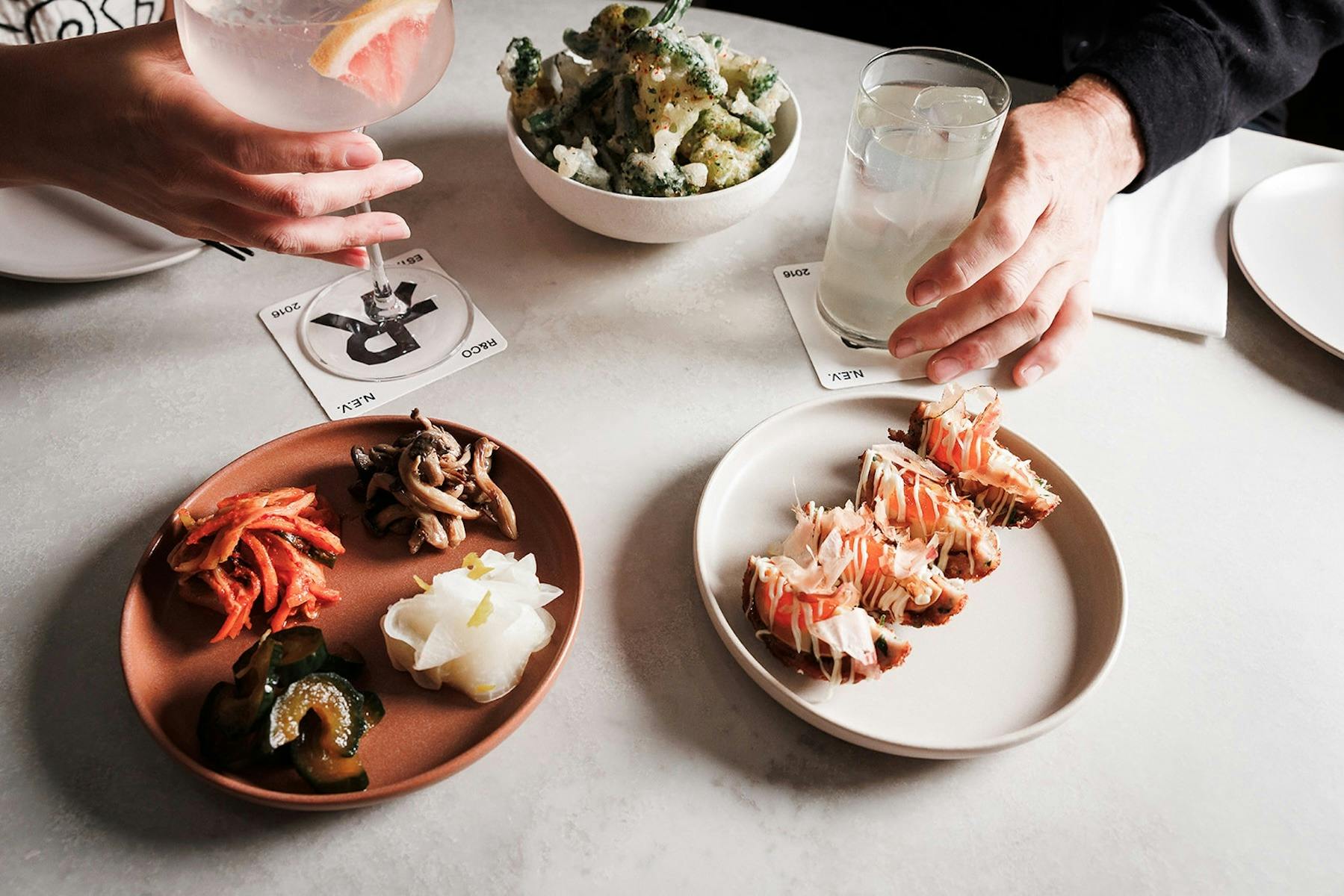 A white table is set with meals and two cocktails.