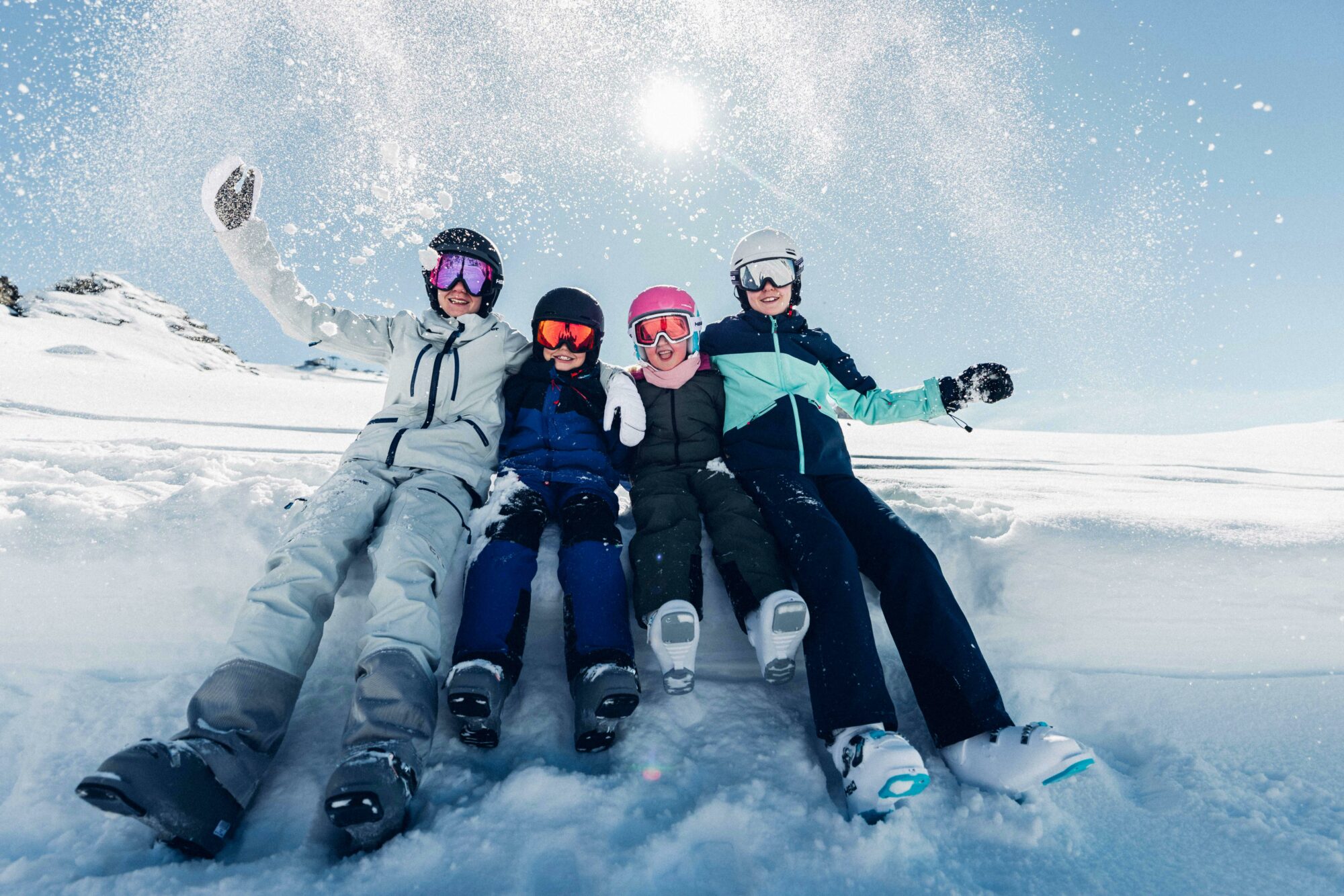 4 kids in the snow taking a break from skiing
