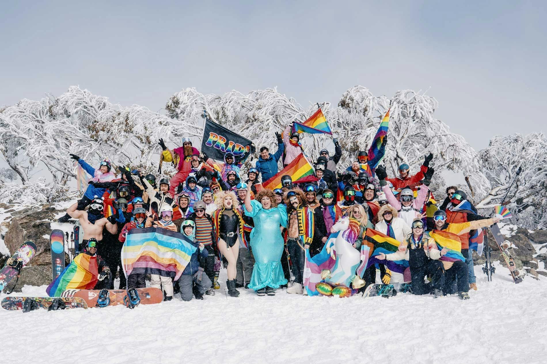 Participants for ski week in rainbow ski outfits and rainbow flags on the snow