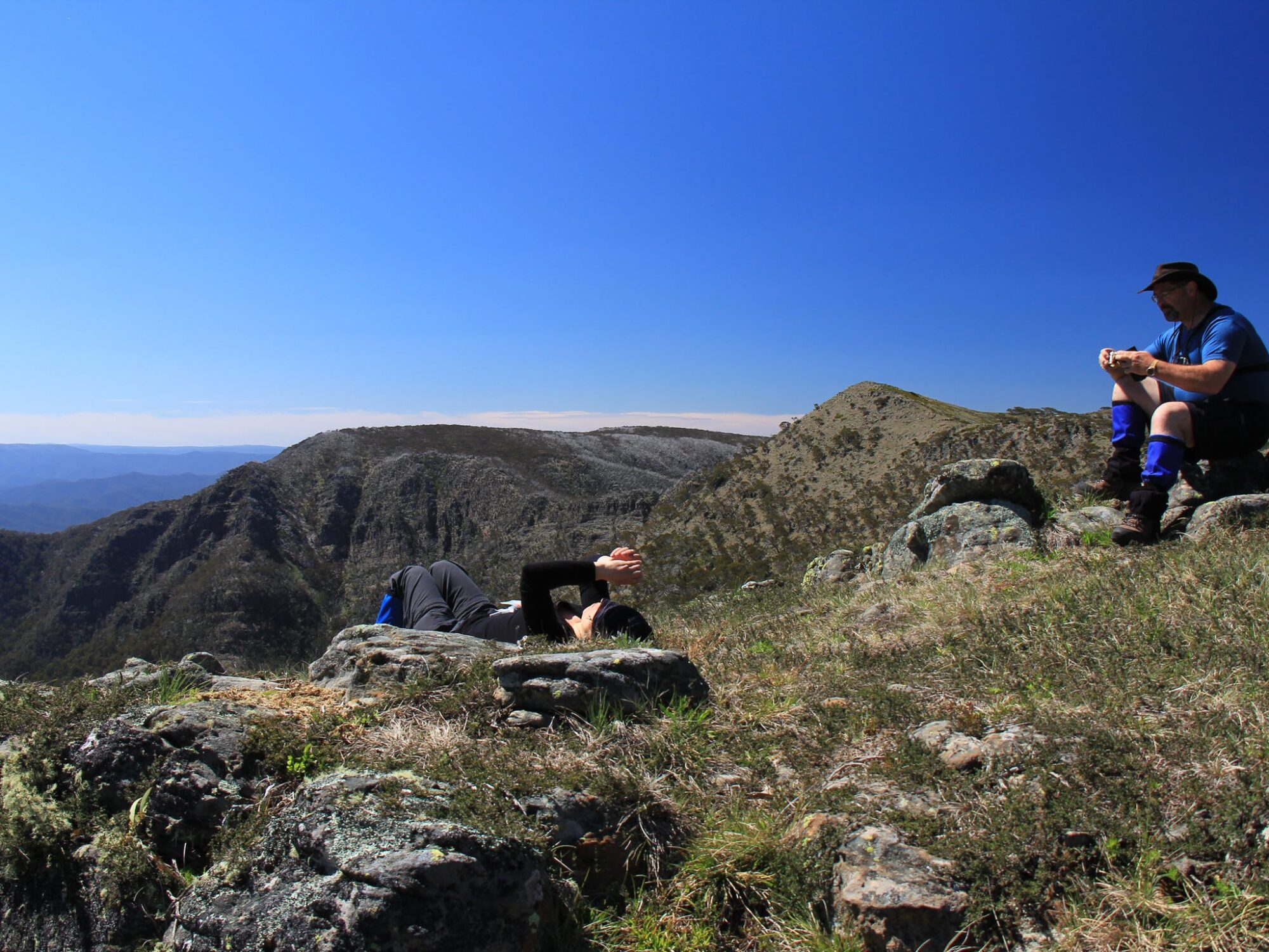 A couple of hikers resting after a big ascent on a saddle between Mt Howitt and The Crosscut Saw.