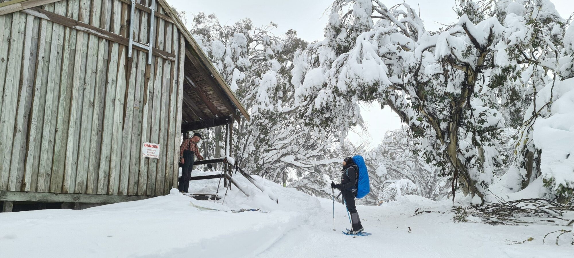 A hiker being greeted by another adventurer into the Bluff Spur Memorial Hut.