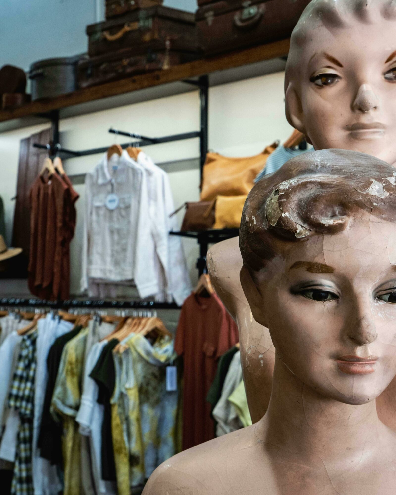 Two mannequins in front of a selection on clothes