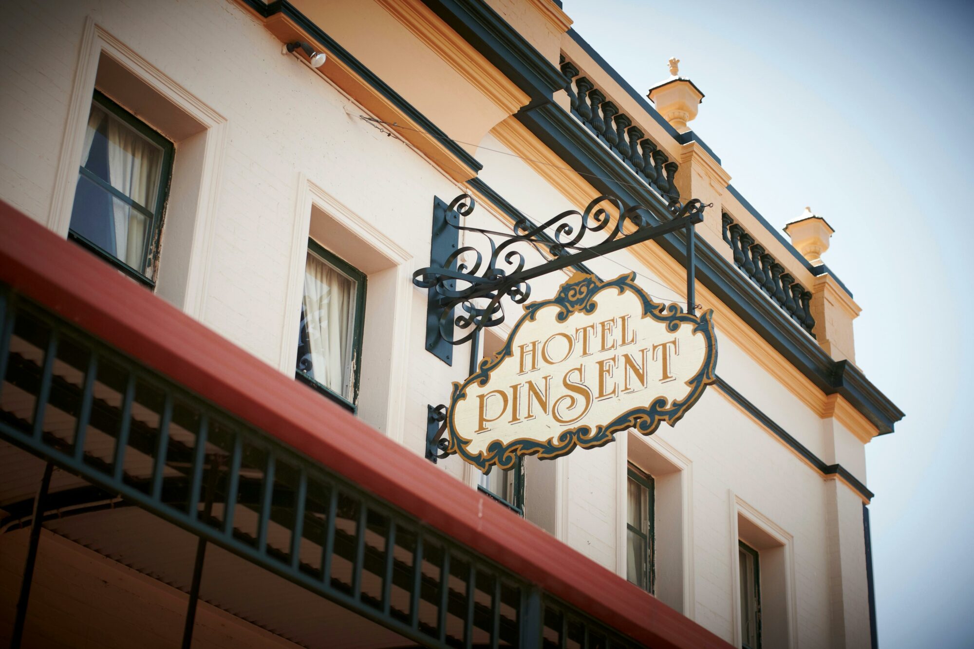 Upstairs of Historic hotel, Iron sign with Hotel Pinsent on it, bedroom windows with curtains