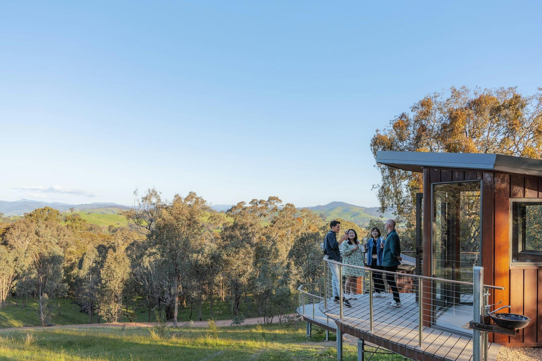 Guests relax with drinks on the deck of the Swiftcrest Tasting Pod, High Country views.