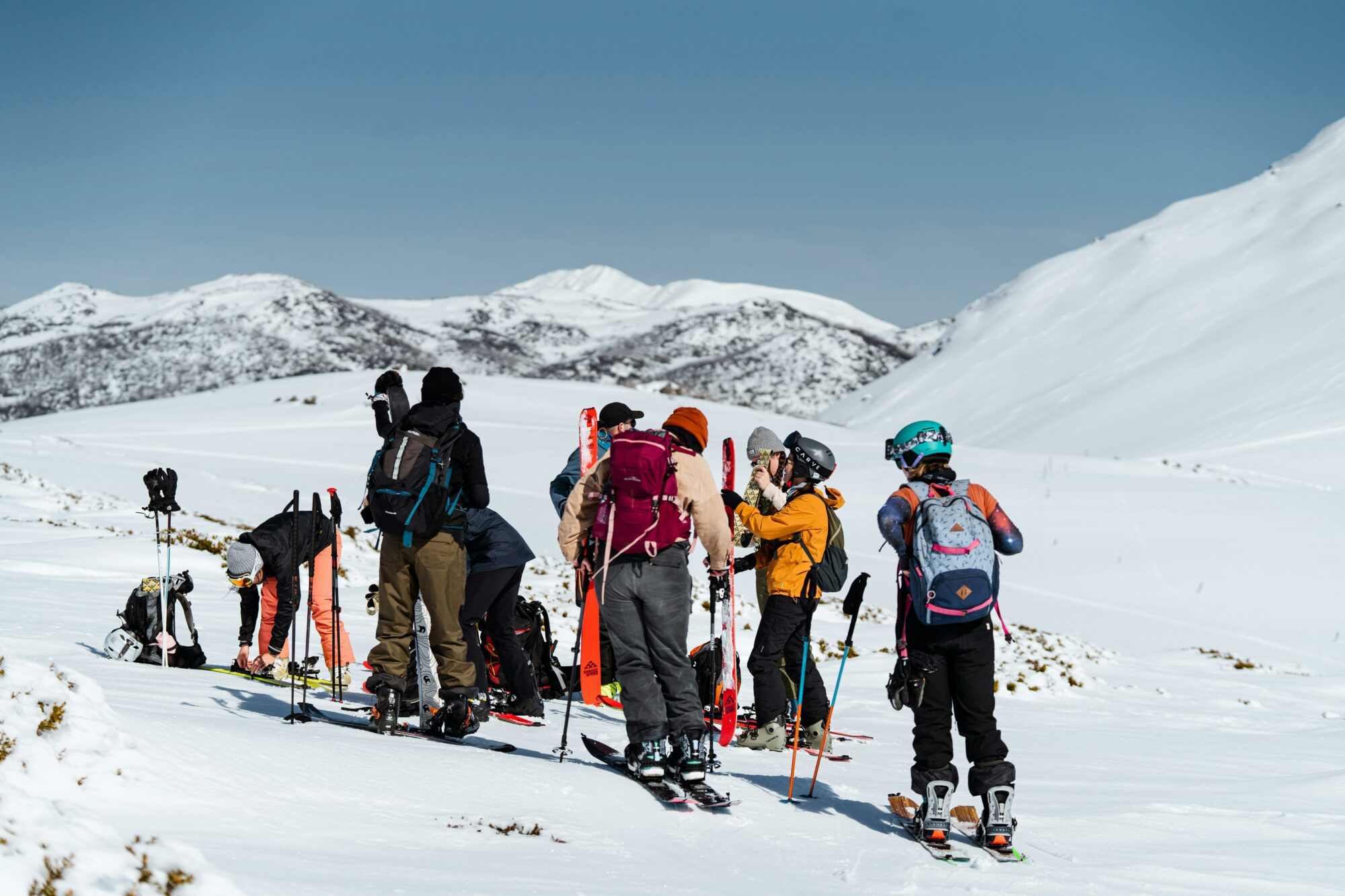group on a snow capped mountain with snow gear and skis