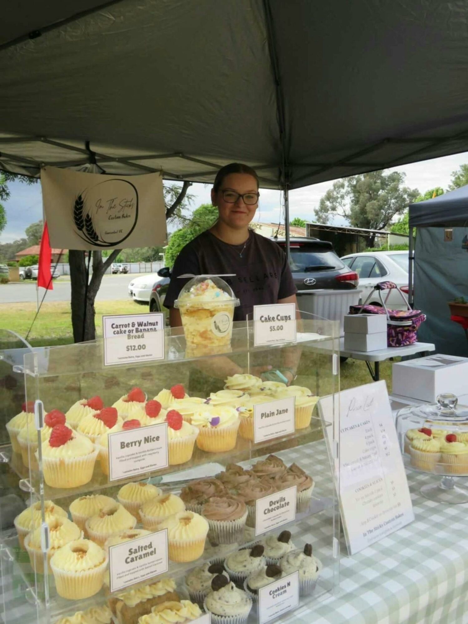 Young lady in black shirt stands behind cupcakes at the Devenish Market