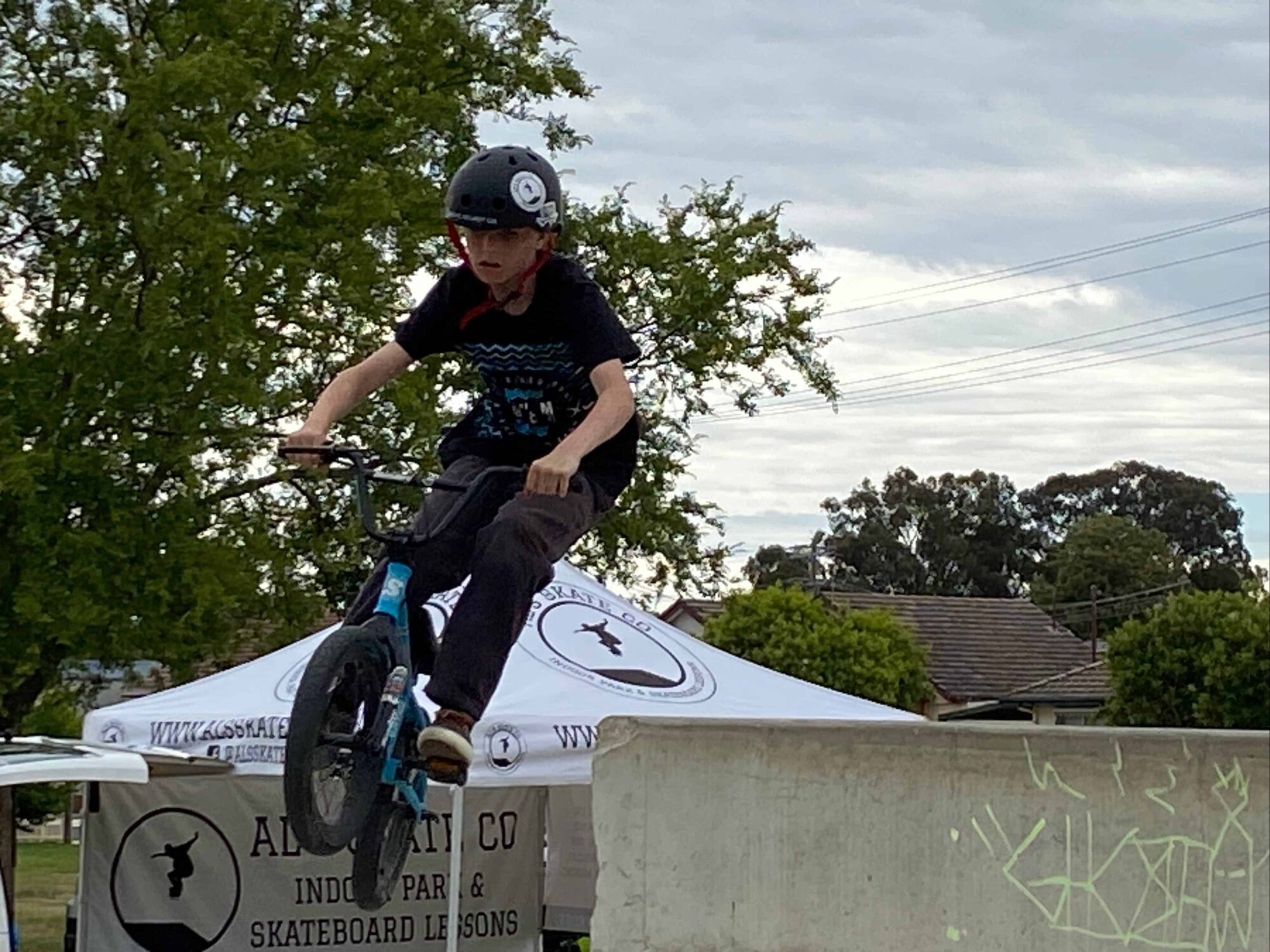 BMX Bike rider jumping in the air with tree behind