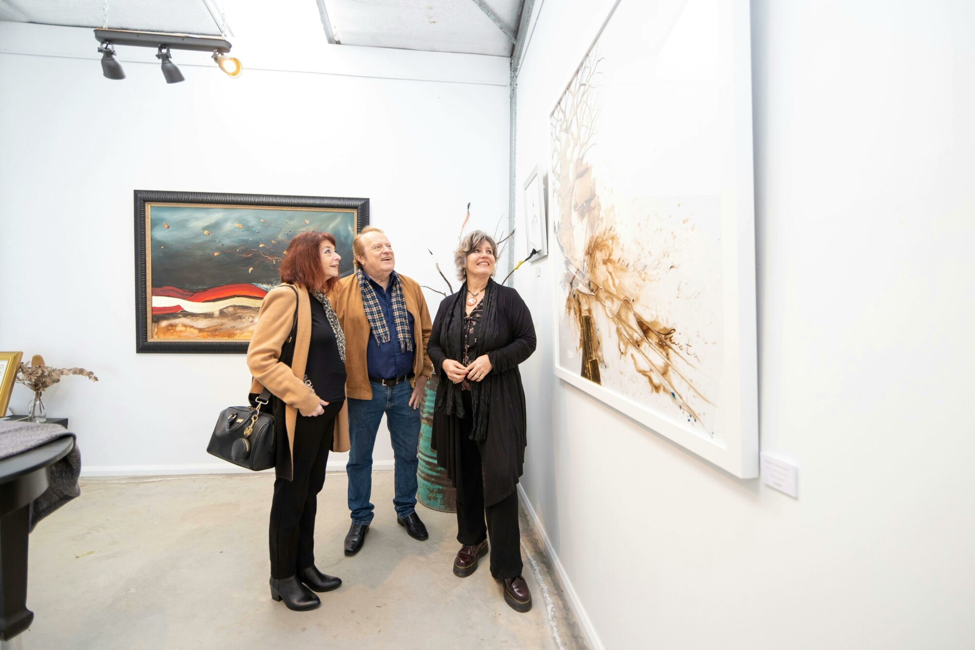 three people enjoying looking at large artworks in a private gallery