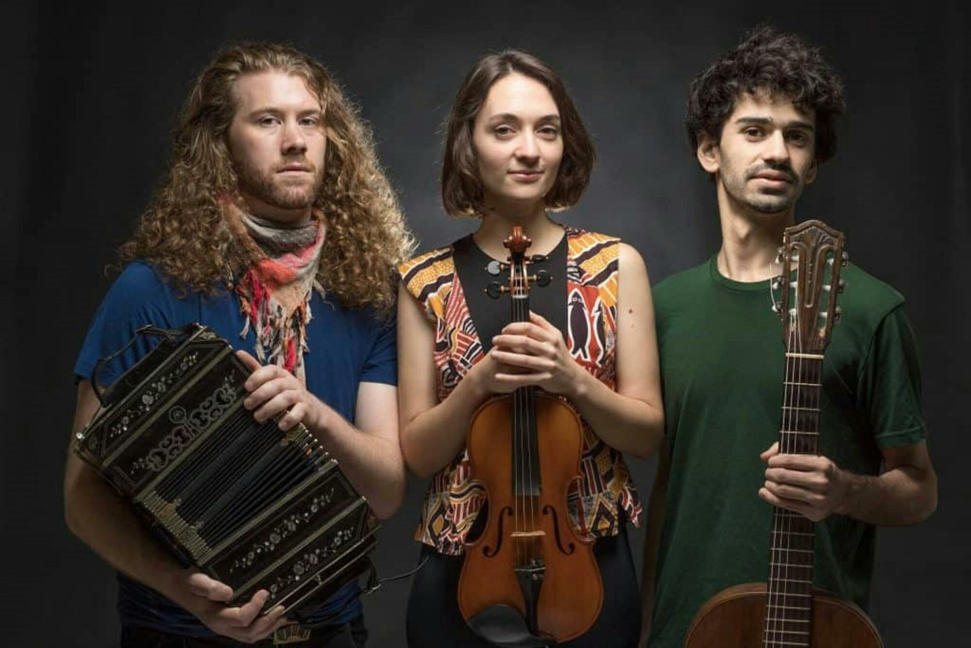 Three musicians holding a small accordion, violin and guitar