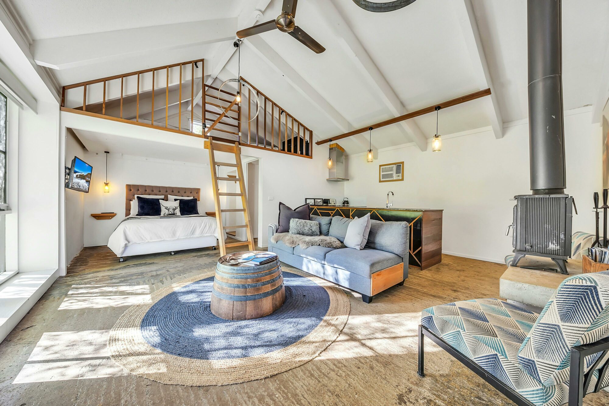 Loft with bed and couch and a ladder.