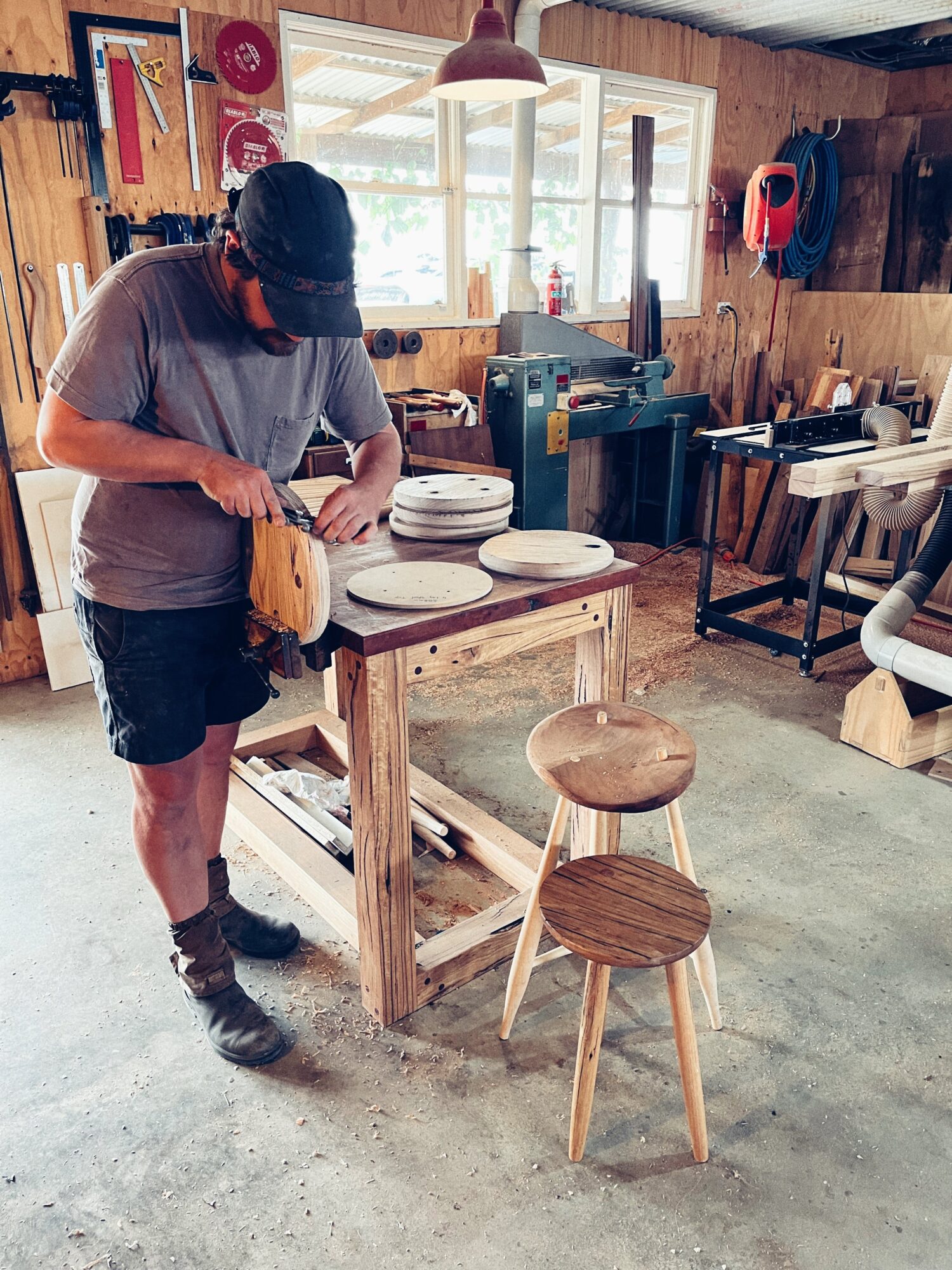 Andy uses hand tools to carve stool seats.