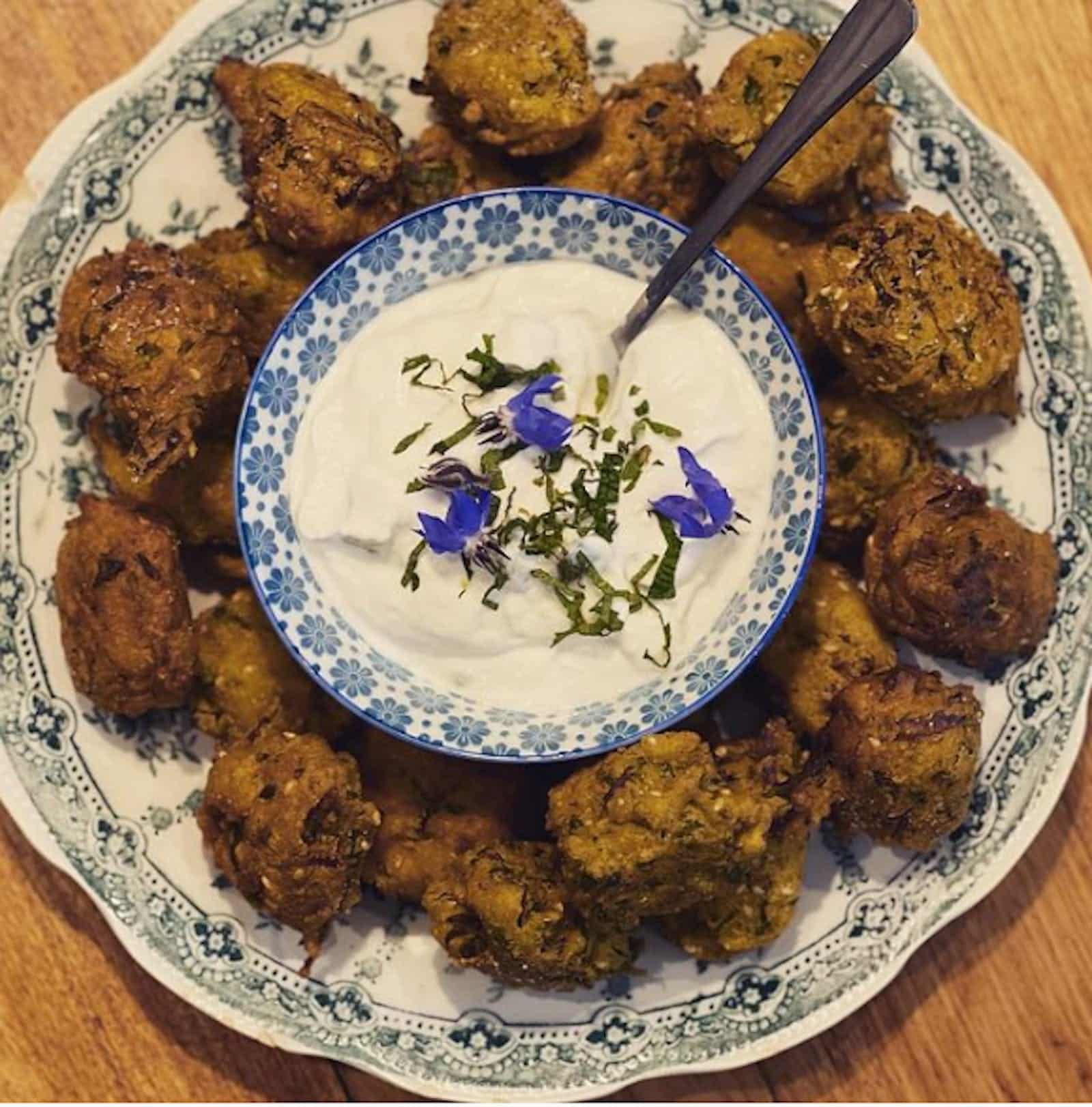 Vintage plate with fried fritters surrounding a blue bowl of  white paste with blue flowers