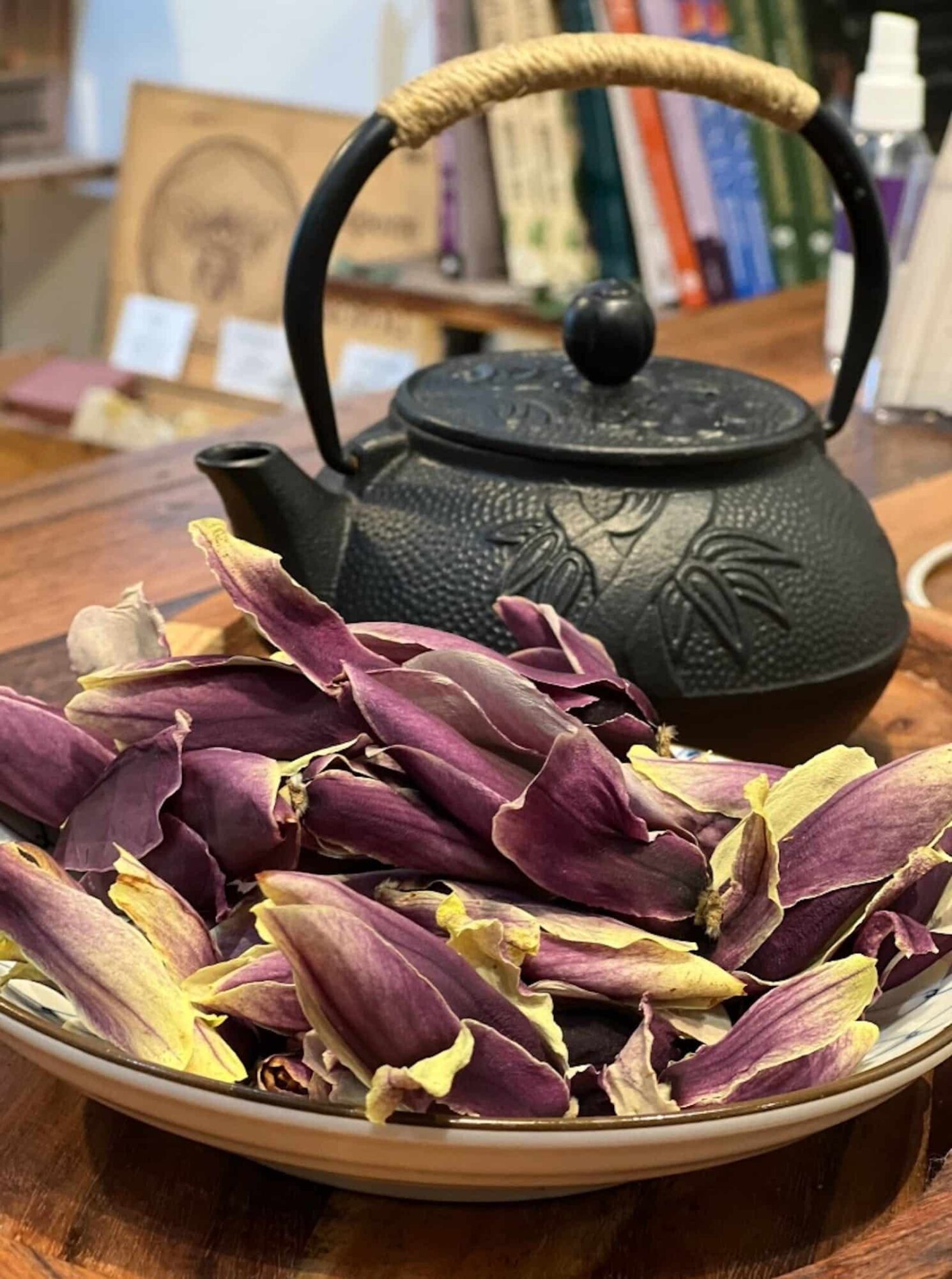 Dried pink flowers in front of a black tea pot