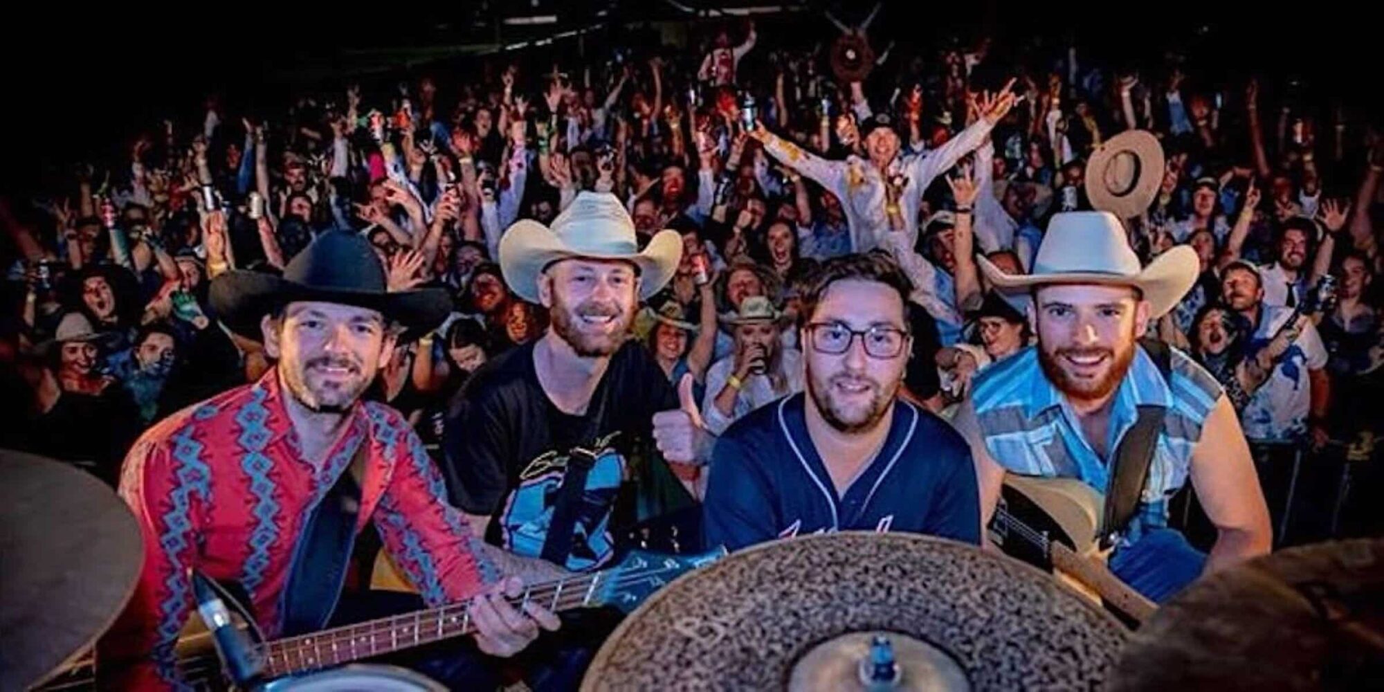 Crowd grinning at the camera well into a night of fun and music.