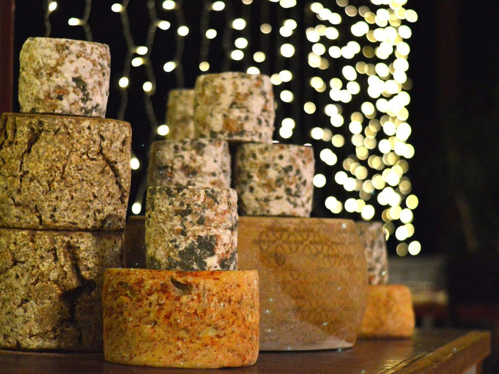 3 stacks of wheels of Milawa Cheese with fairy lights in the background