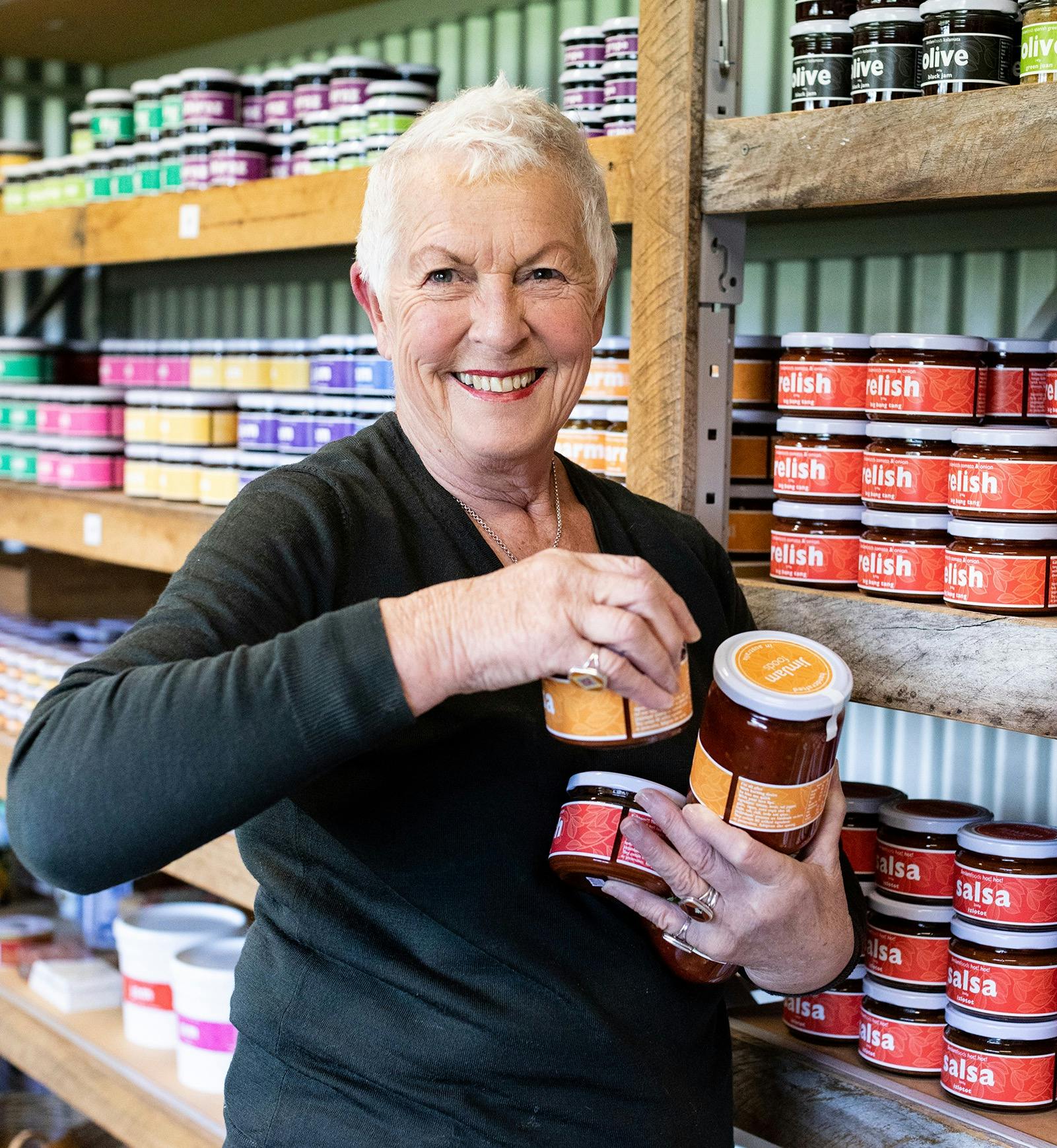 Maggie at the JimJam Farmgate holding jars and smiling.